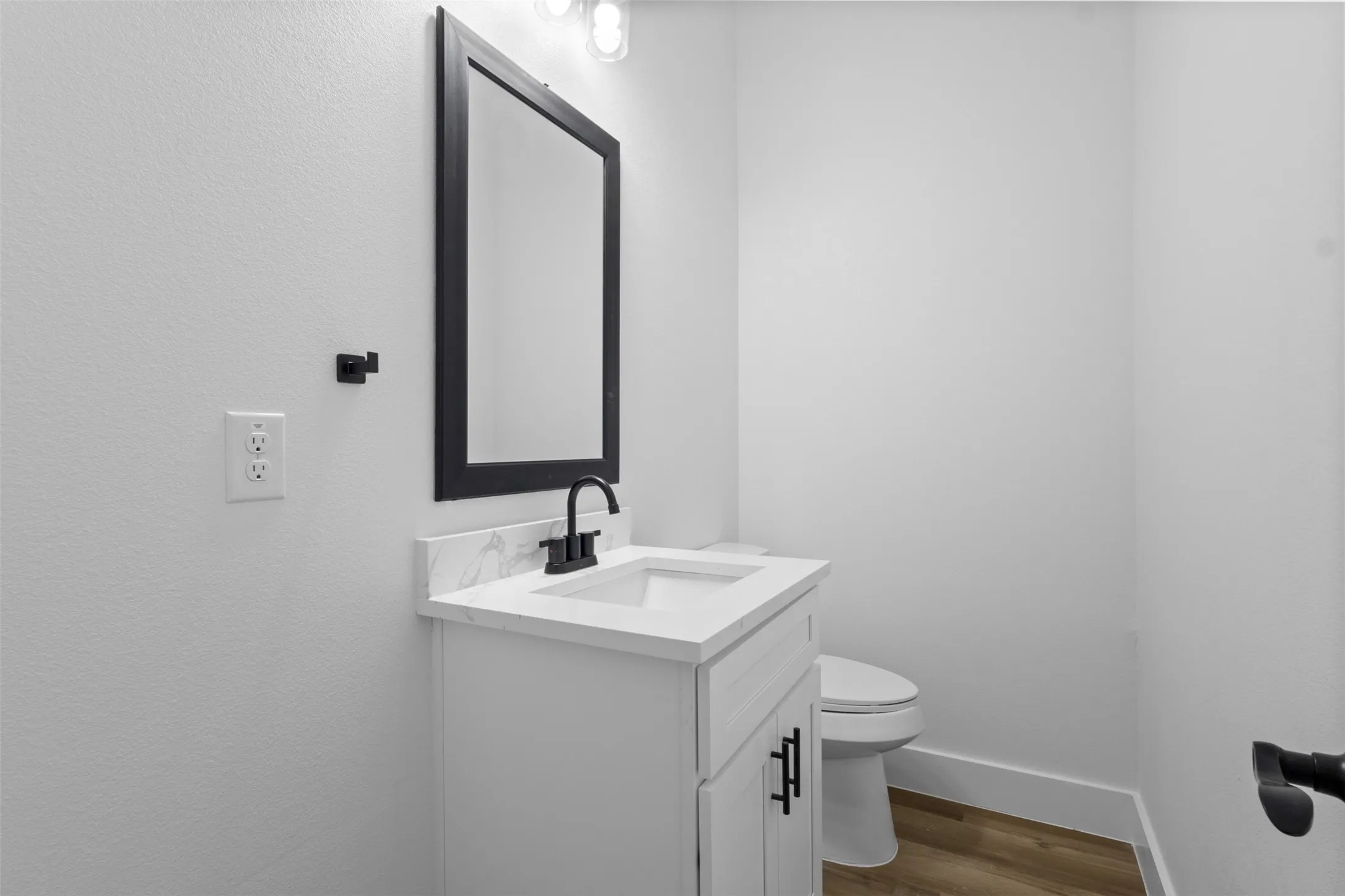 White vanity with matte black hardware, integrated sink, and a framed mirror