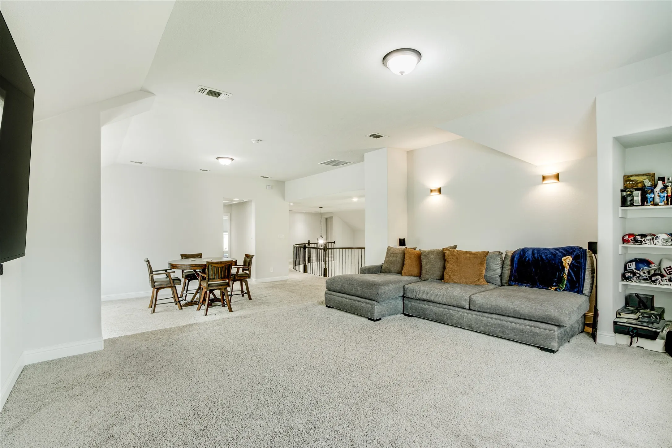 Spacious carpeted room featuring recessed lighting, ceiling-mounted light fixtures, and wall sconces