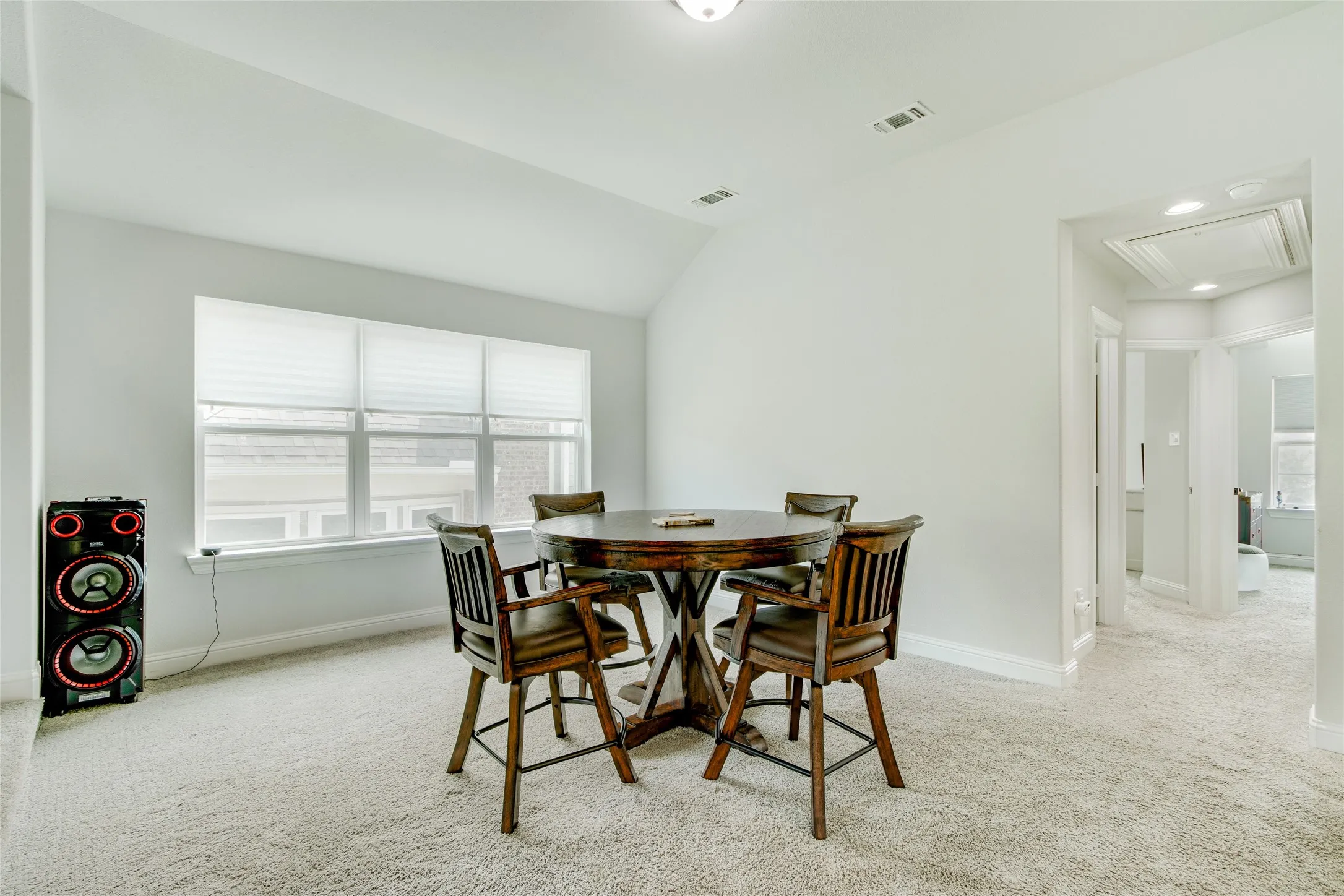 Room featuring a vaulted ceiling, large window, and carpet flooring