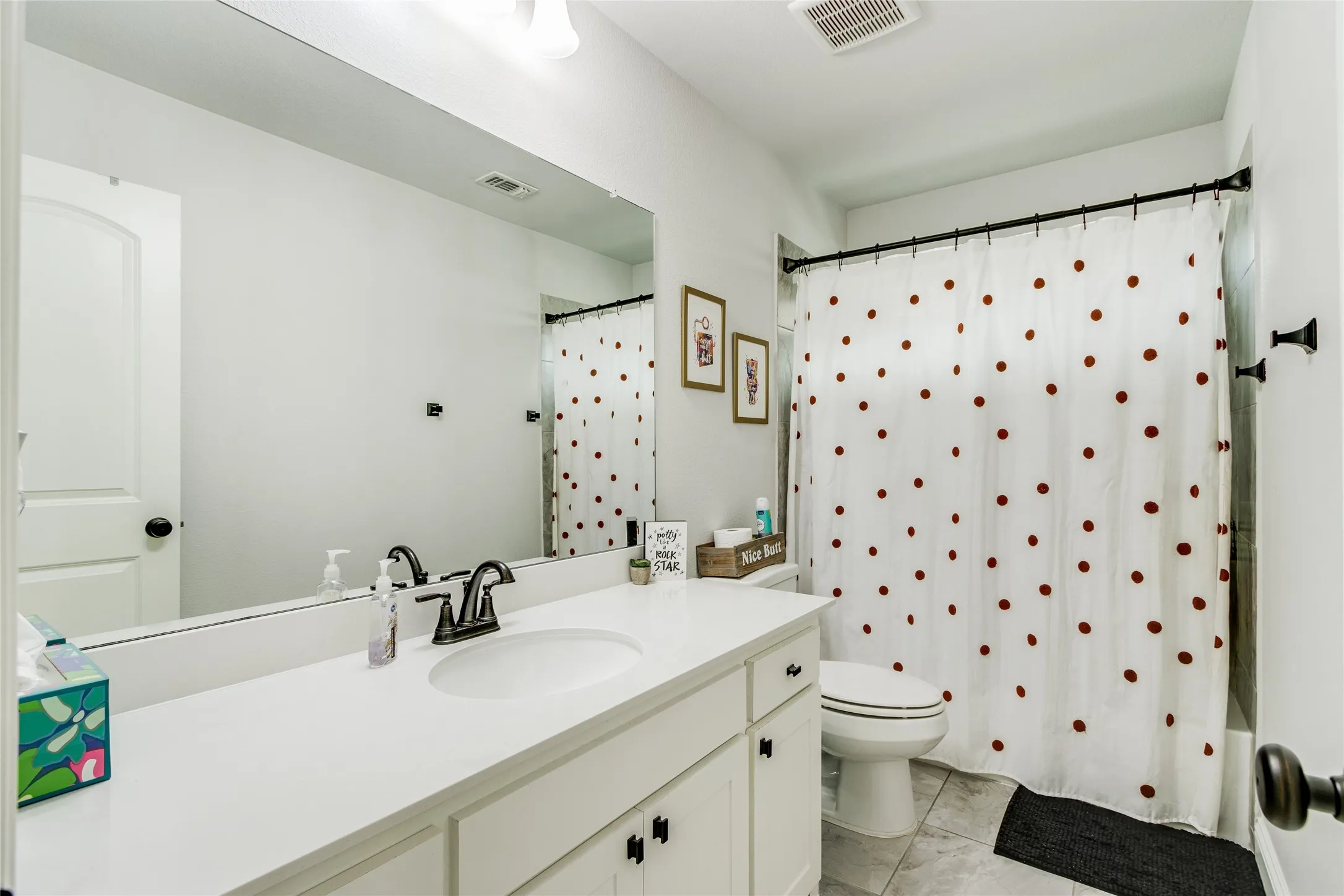 White vanity with dark hardware, white rectangular countertop, undermount sink, and dark faucet