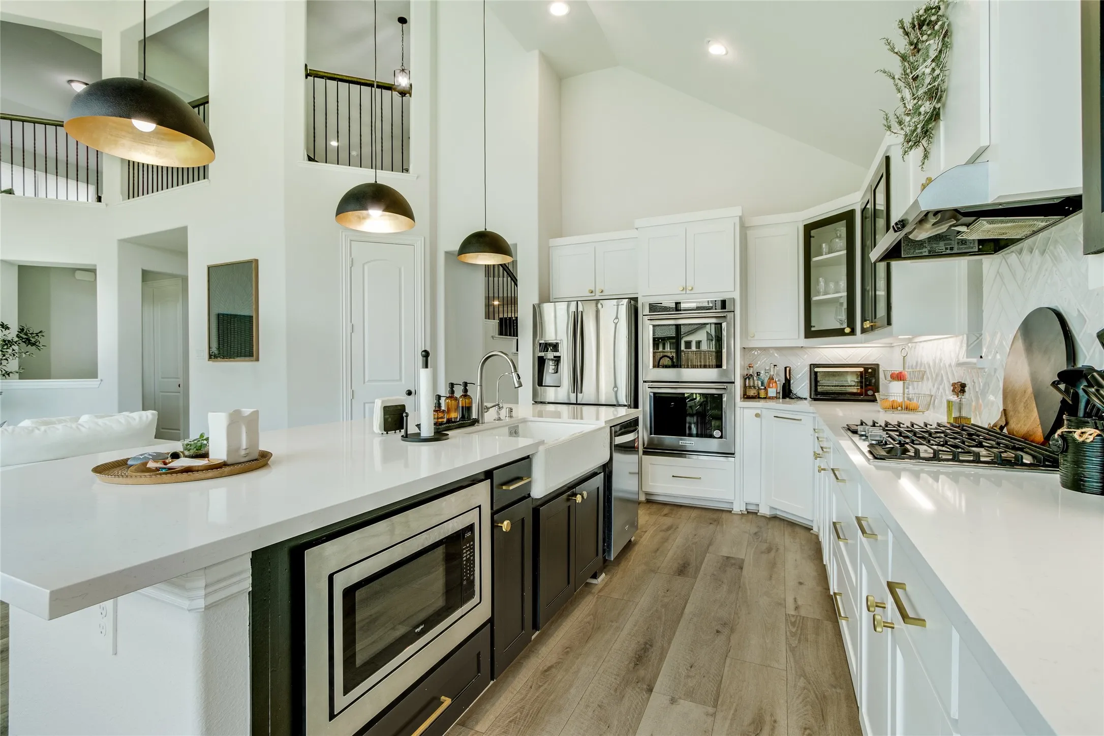 Kitchen featuring wood-finish flooring, white cabinetry, a white farmhouse sink, stainless steel appliances, and a gas range