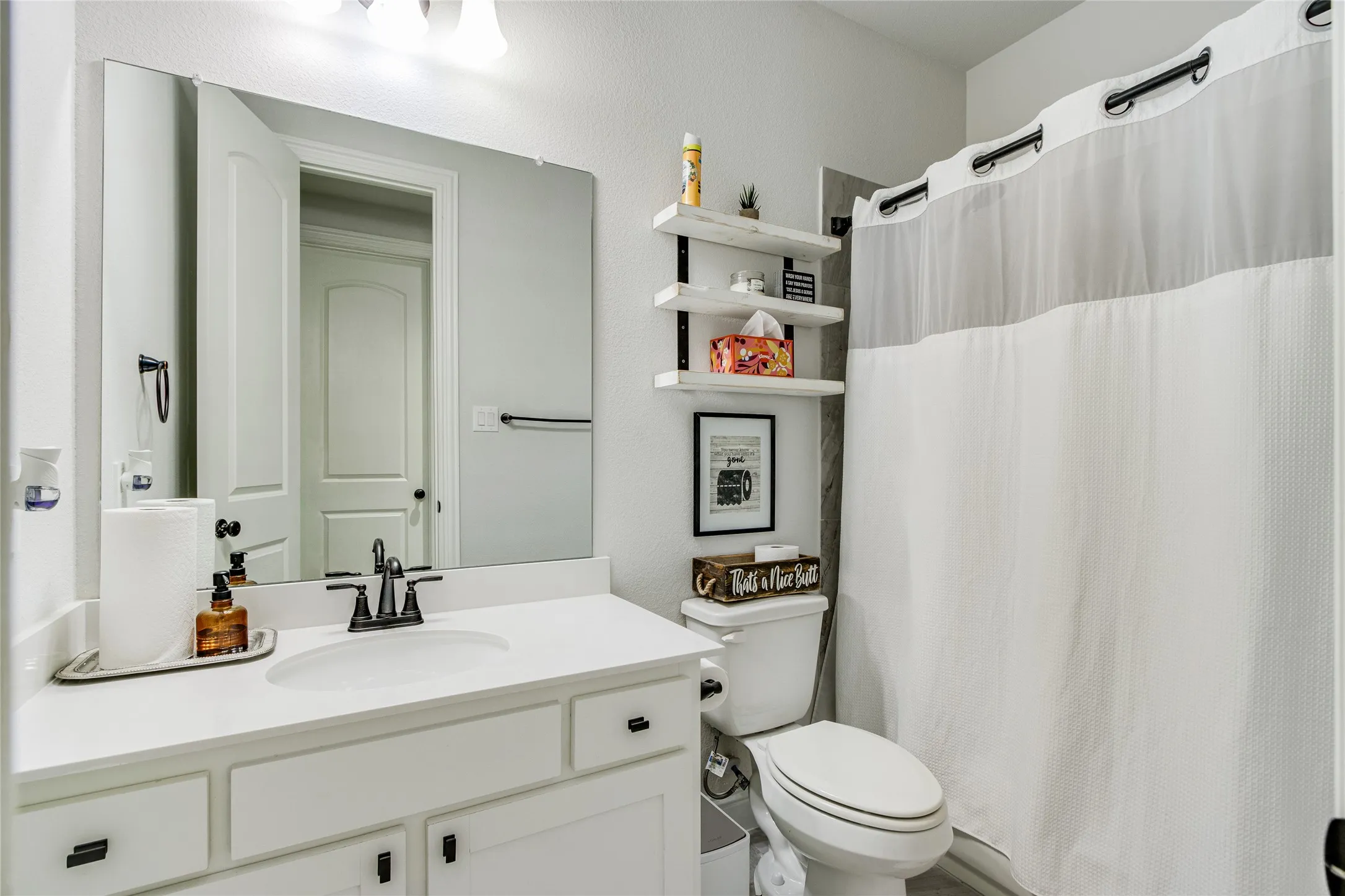 Bathroom featuring a white vanity with integrated sink, black fixtures, and built-in shelving
