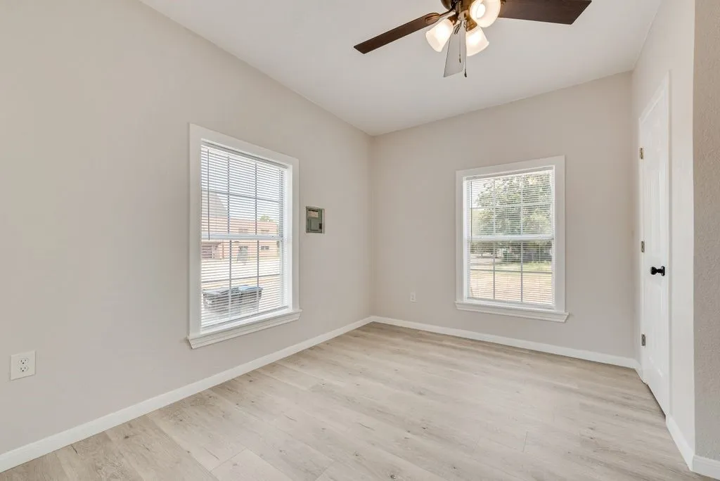 Light wood-finish flooring, white trim, and a ceiling fan with integrated lighting