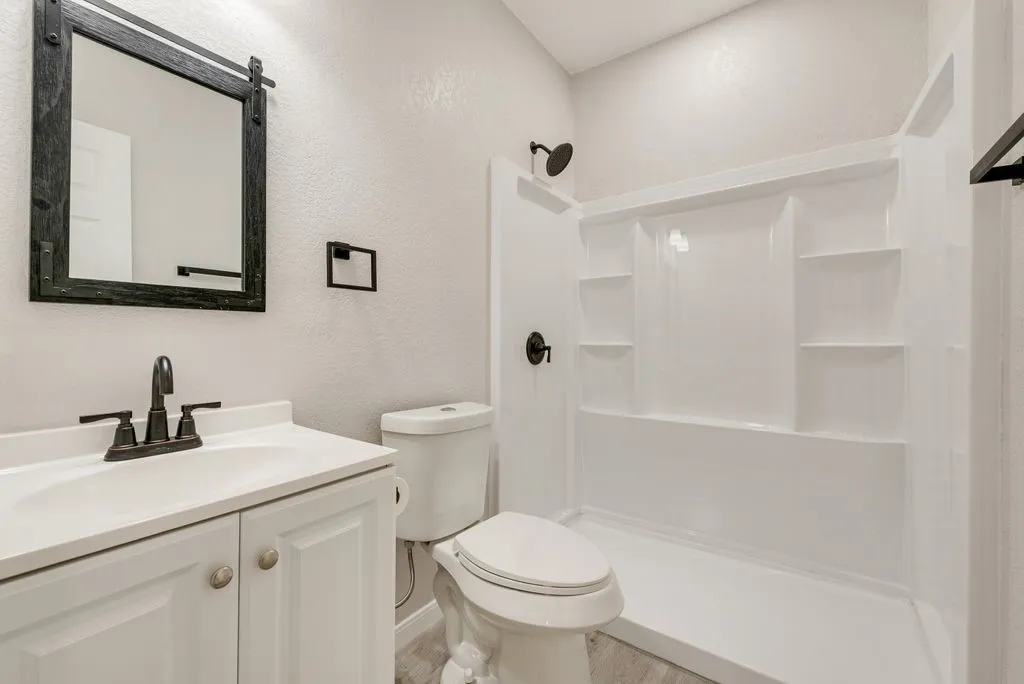 White vanity with integrated sink, bronze-finish faucet, and a black-framed mirror
