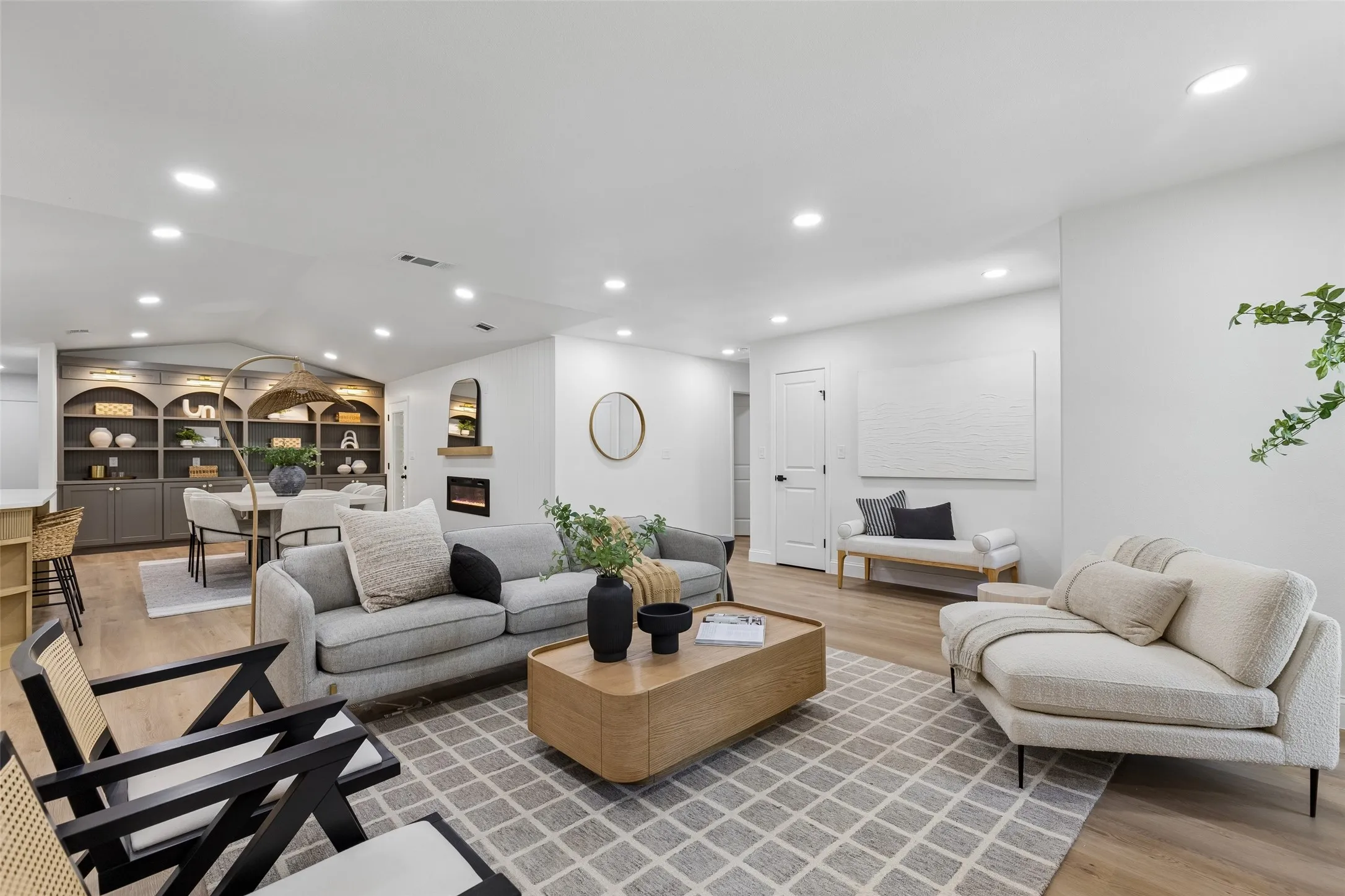 Recessed lighting throughout, wood-finish flooring, built-in shelving, and a modern fireplace