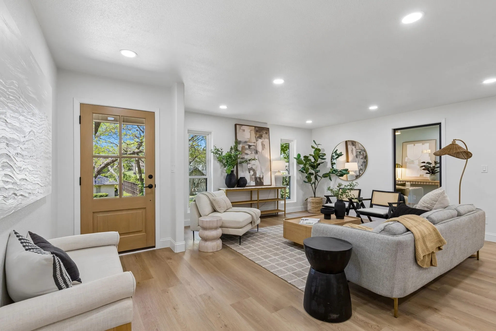 Light wood-finish flooring throughout, recessed ceiling lighting, and a front entry door with glass panels