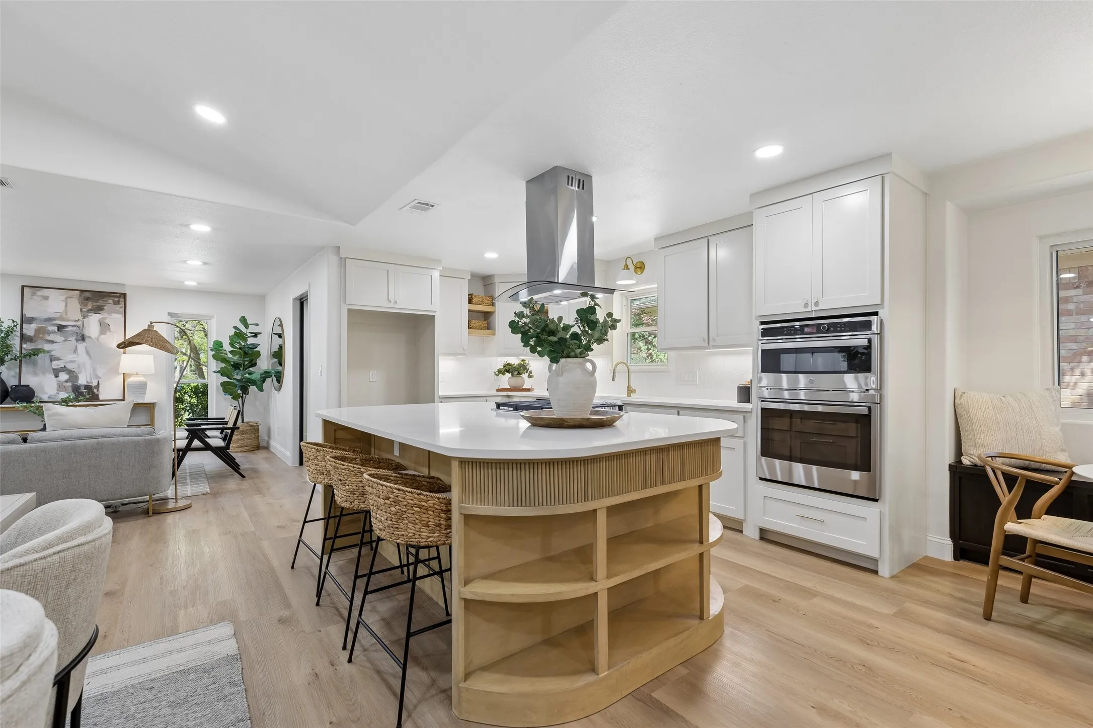 Central kitchen island with wood-finish shelving, stainless steel appliances, white cabinetry, and wood-finish flooring