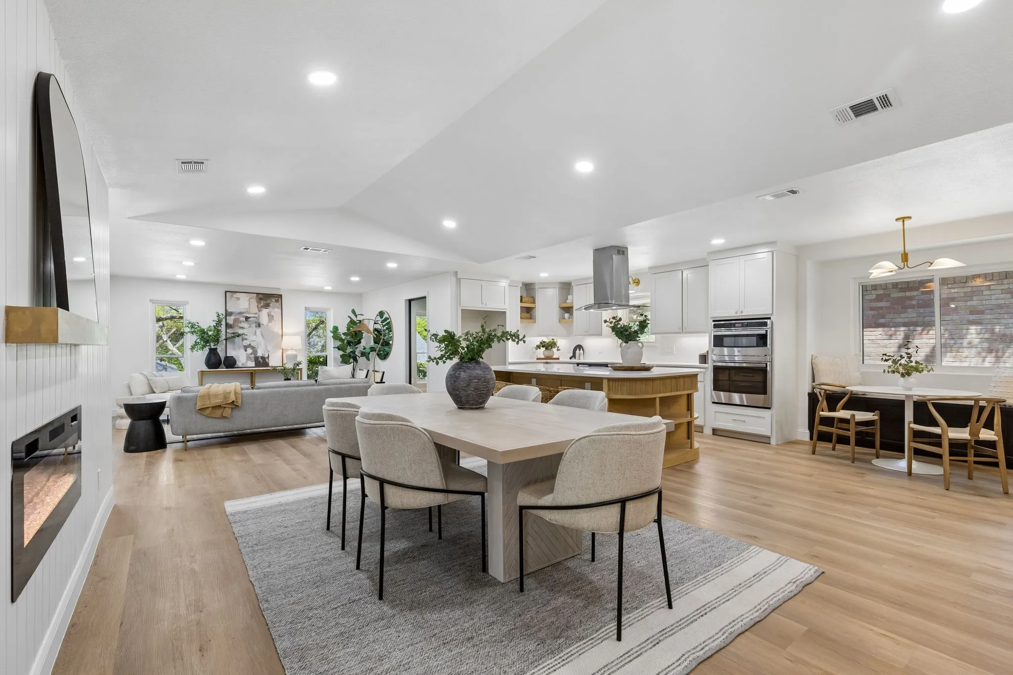 Open-concept living space featuring wood-finish flooring, recessed lighting, a built-in fireplace, and a kitchen island with built-in​​‌​​​​‌​​‌‌​‌‌​​​‌‌​‌​‌​‌​​​‌​​ shelving