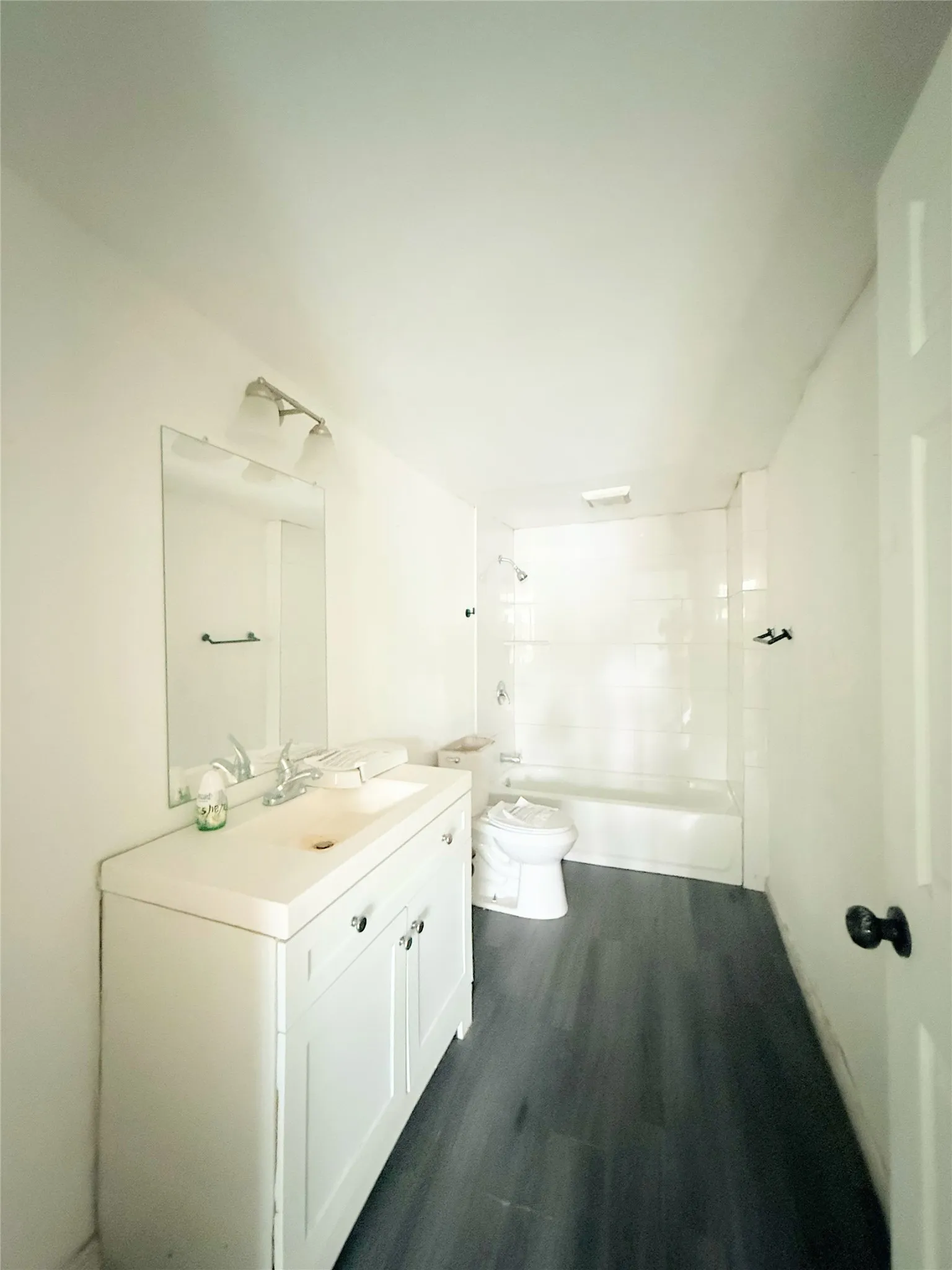 White vanity with chrome hardware, rectangular mirror, and wall-mounted light fixture