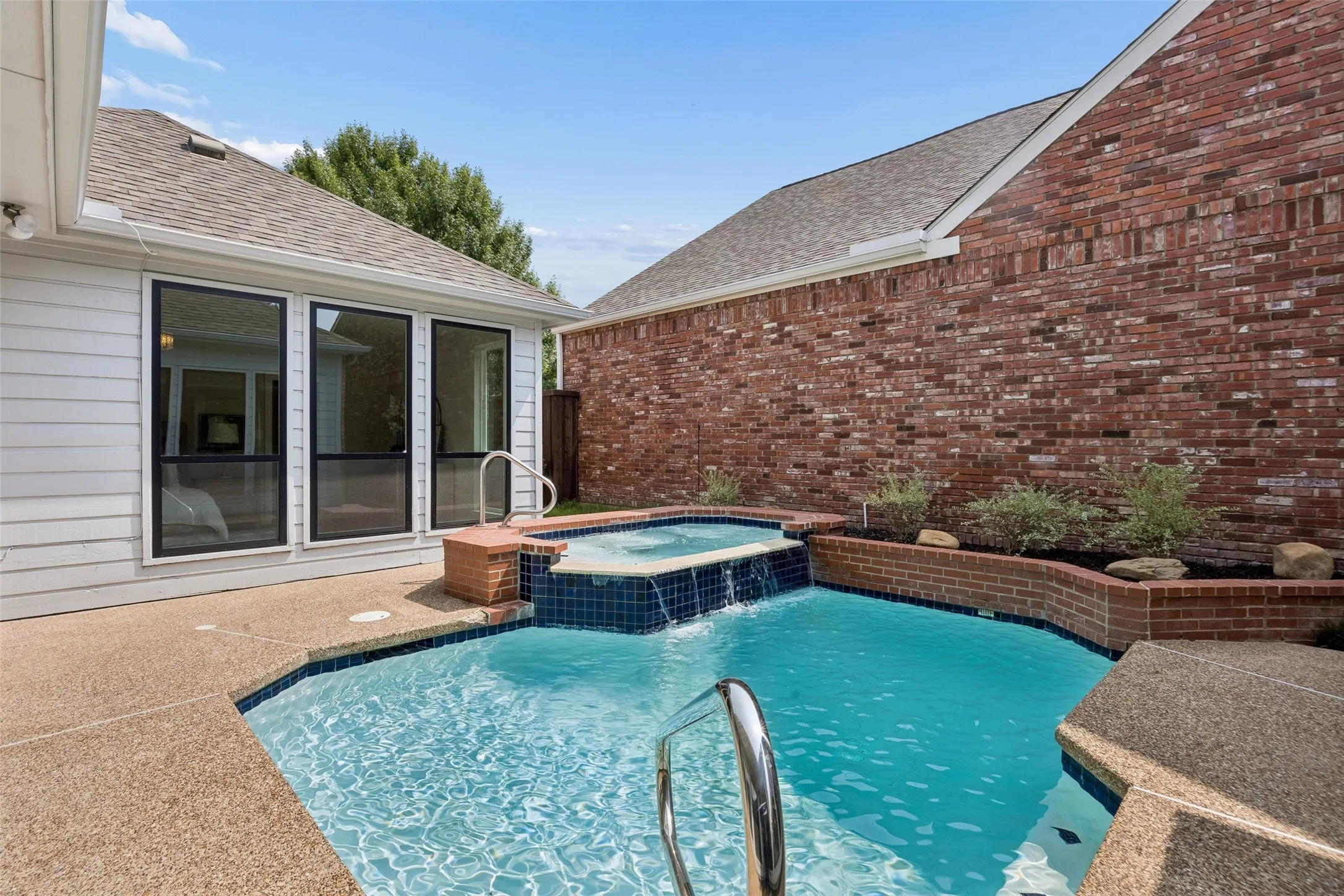 Private backyard featuring a swimming pool with an integrated spa, a waterfall feature.