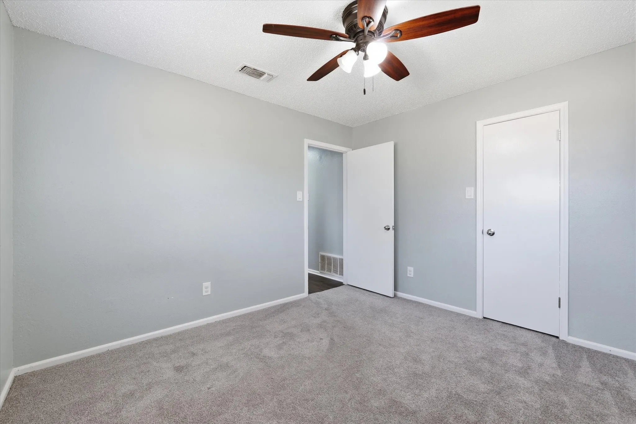 Carpeted flooring, light gray wall paint, white trim, ceiling fan with integrated lighting, and white interior doors