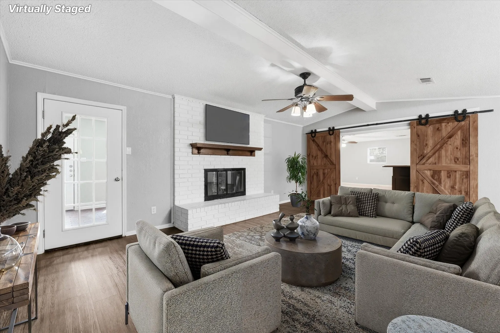 Open-concept living area featuring hardwood flooring, ceiling fan with integrated lighting, and a fireplace with built-in shelving