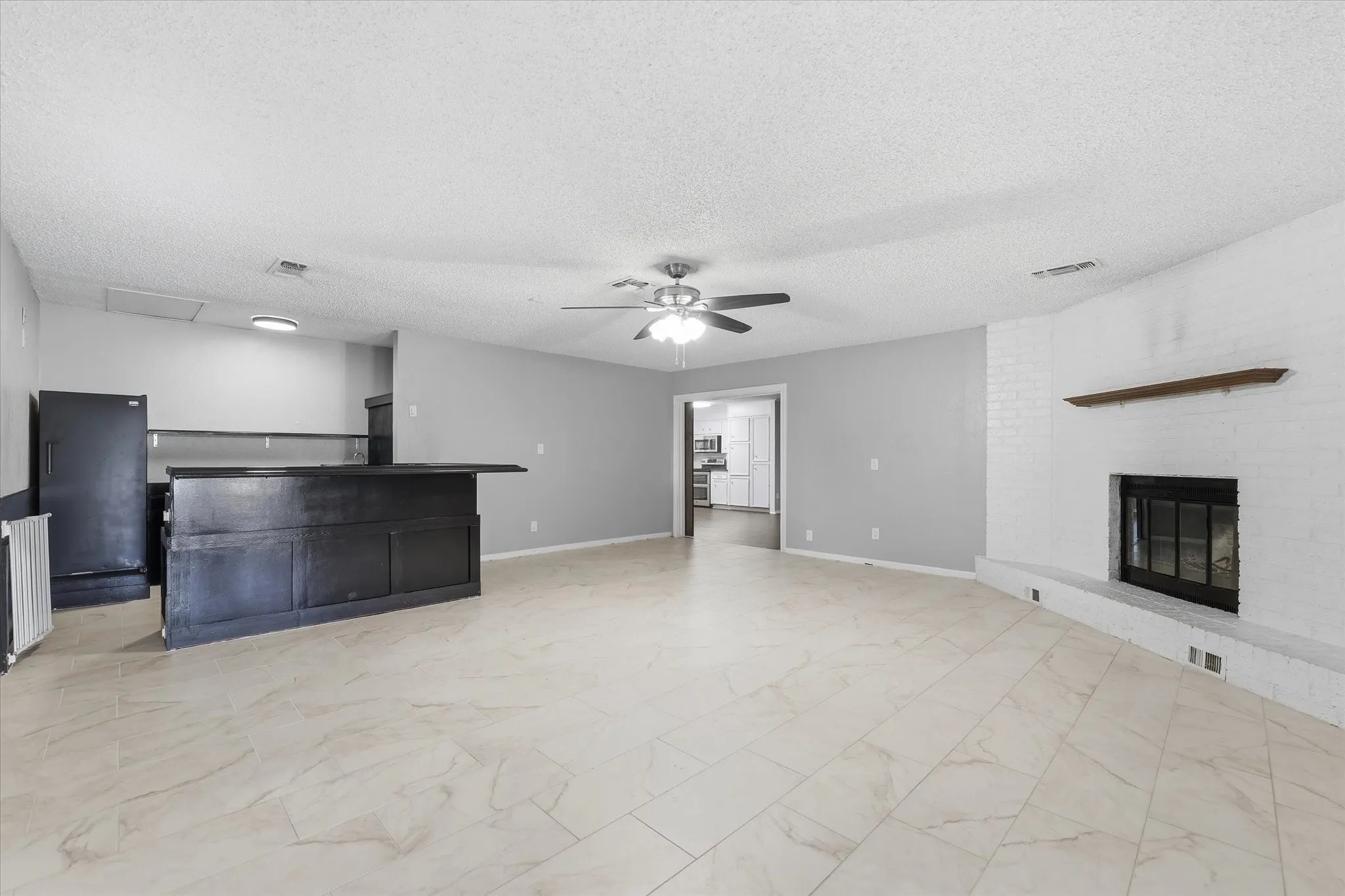 Spacious open-concept living area featuring light wood-finish flooring, recessed ceiling lighting, and a ceiling fan