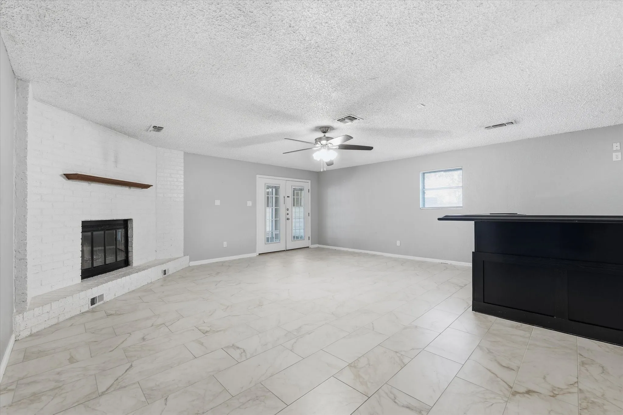 Spacious open-concept living area featuring polished stone-finish flooring, recessed ceiling lighting, and a ceiling fan