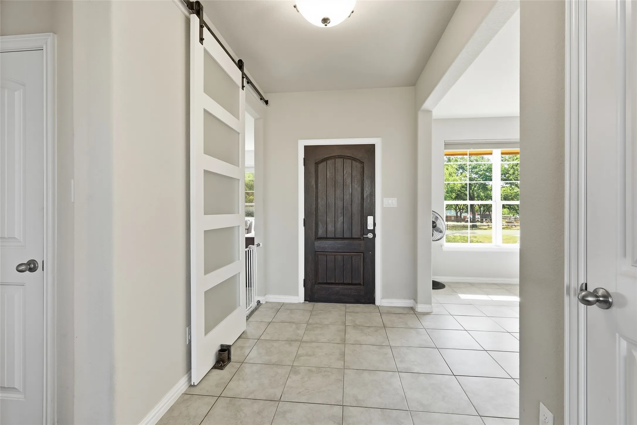 Welcoming foyer showcasing tile flooring, recessed ceiling lighting, and a dark wood entry door with arched detail