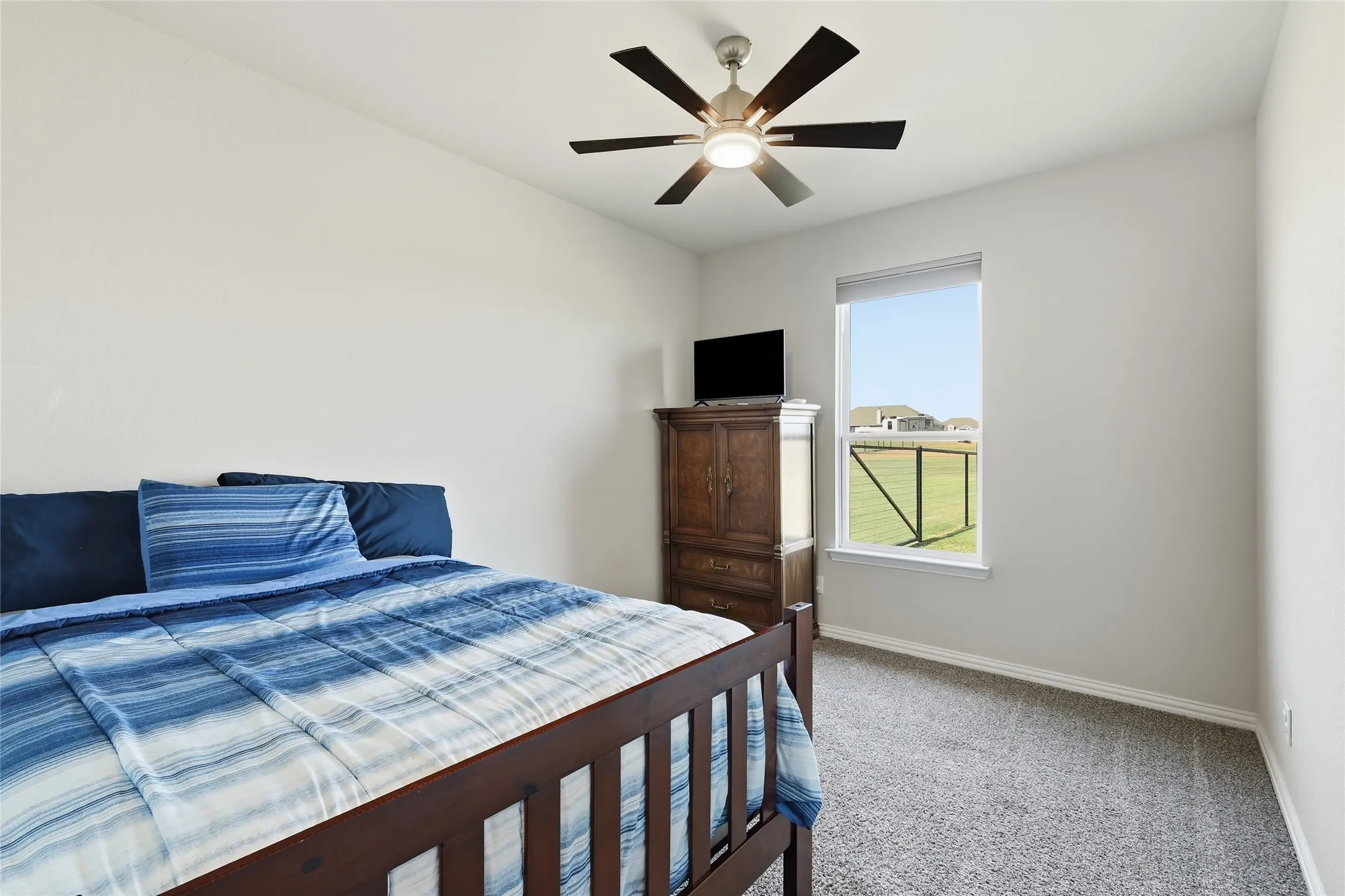Neutral wall paint, ceiling fan, natural light from a single window, and carpet flooring