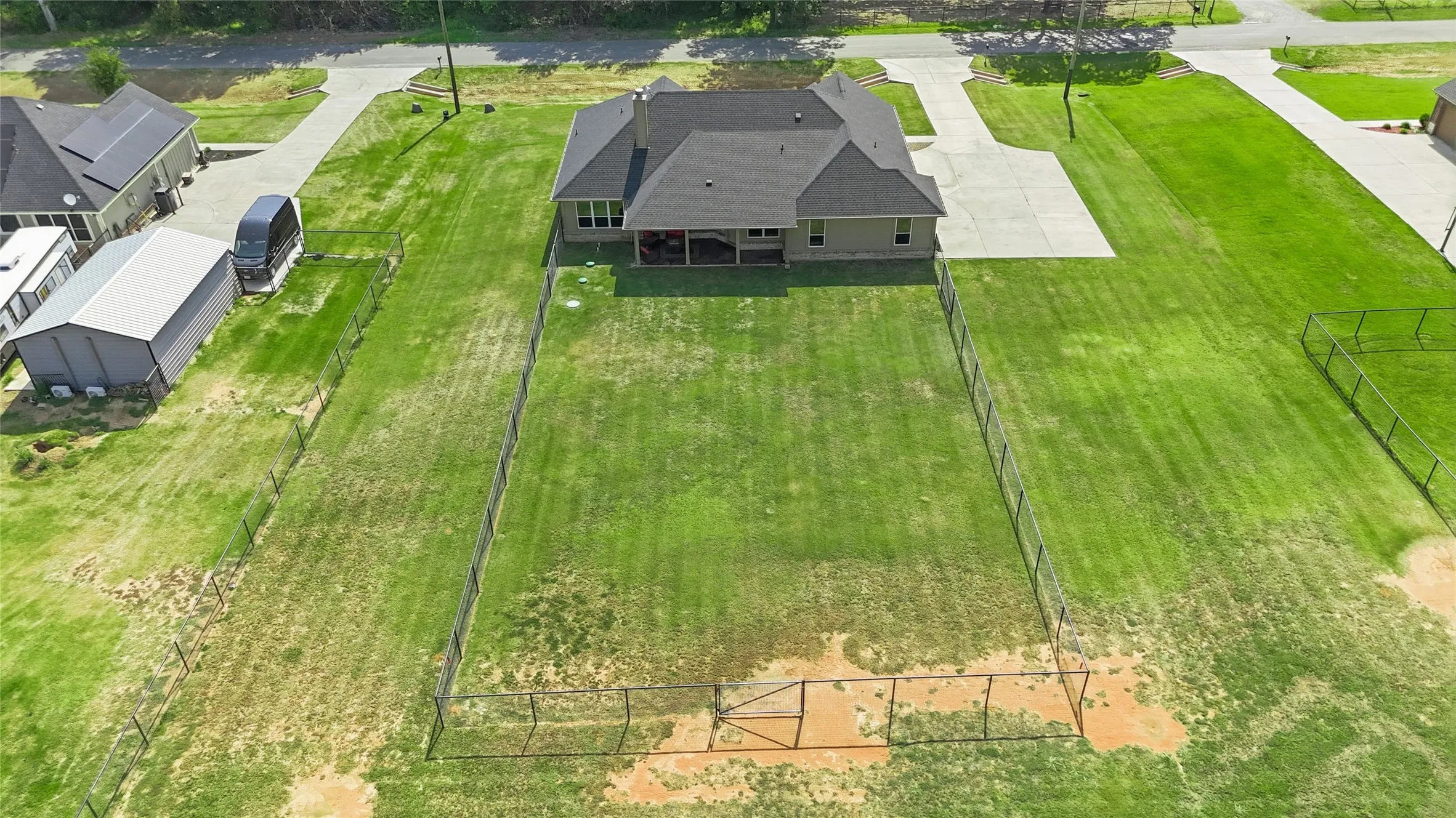 Expansive fenced property featuring a well-maintained lawn and a concrete driveway