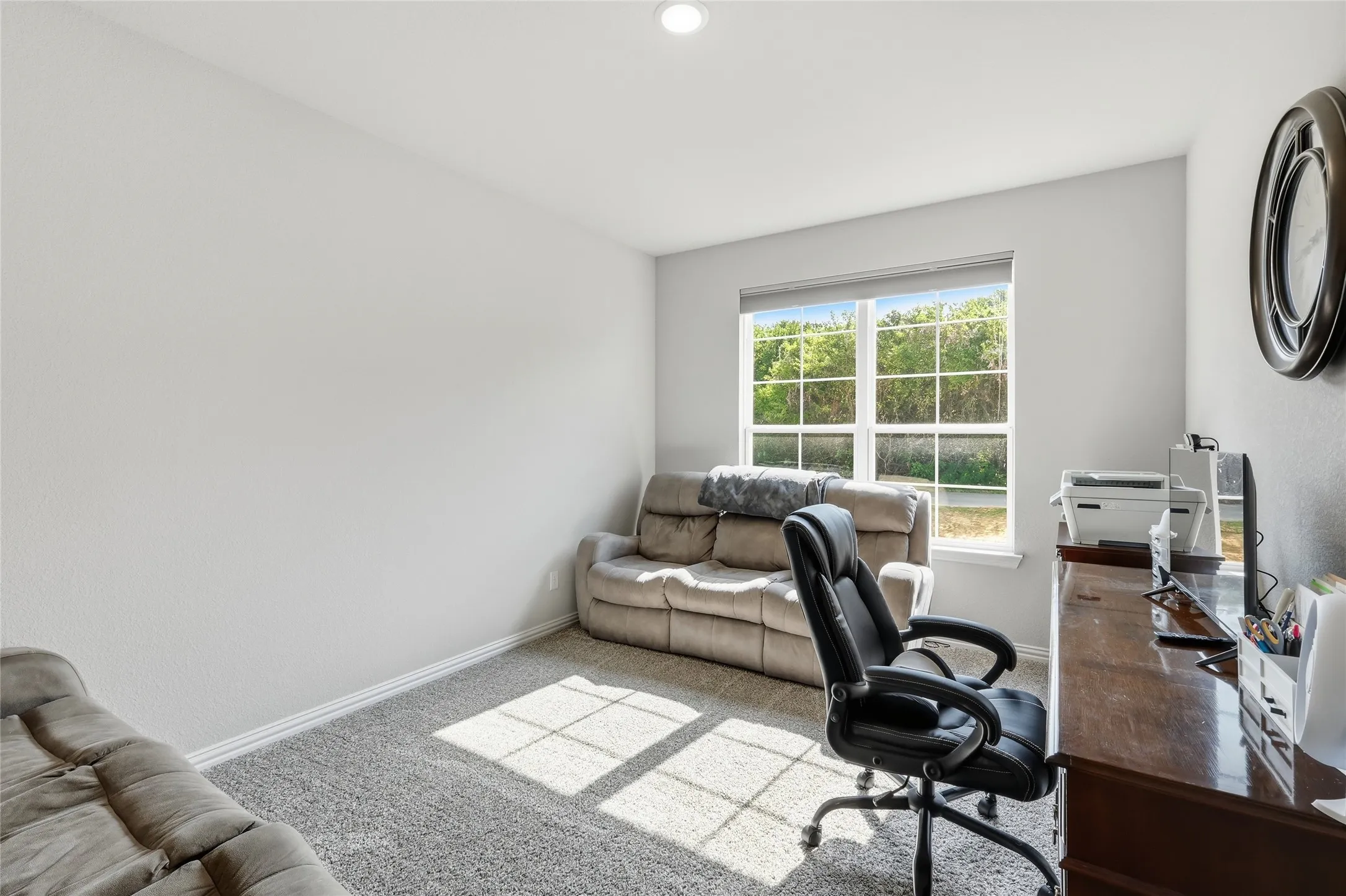 Recessed ceiling lighting, a large window, and light-toned walls