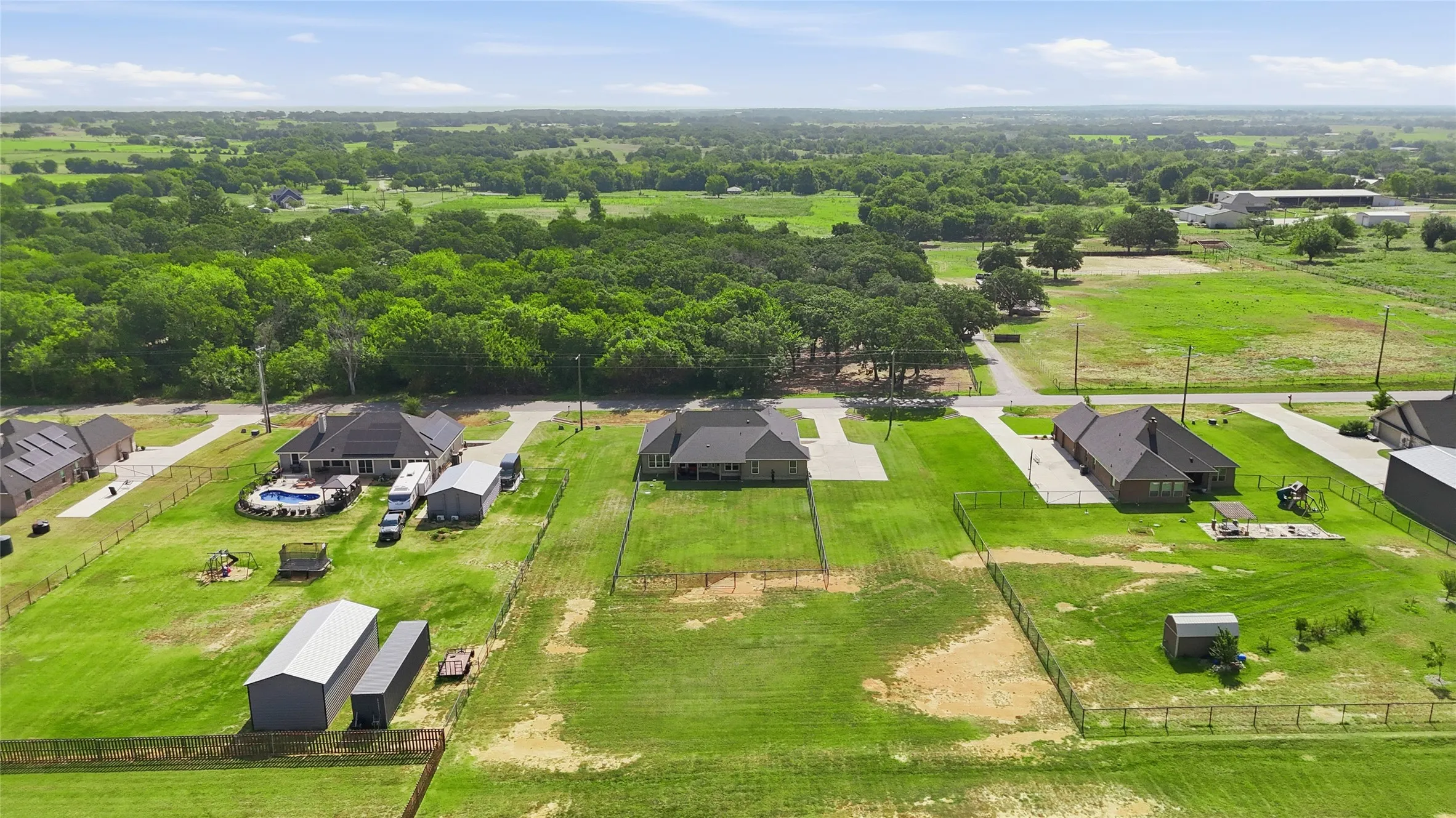 Expansive property featuring a single-story residence with a dark roof and light brick exterior