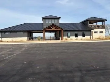 Modern agricultural or commercial facility featuring a metal roof system, clerestory windows for natural light, and a covered entrance portico with exposed timber detailing