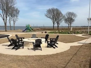 Outdoor fire pit with stone surround, circular concrete patio, and winding concrete pathway