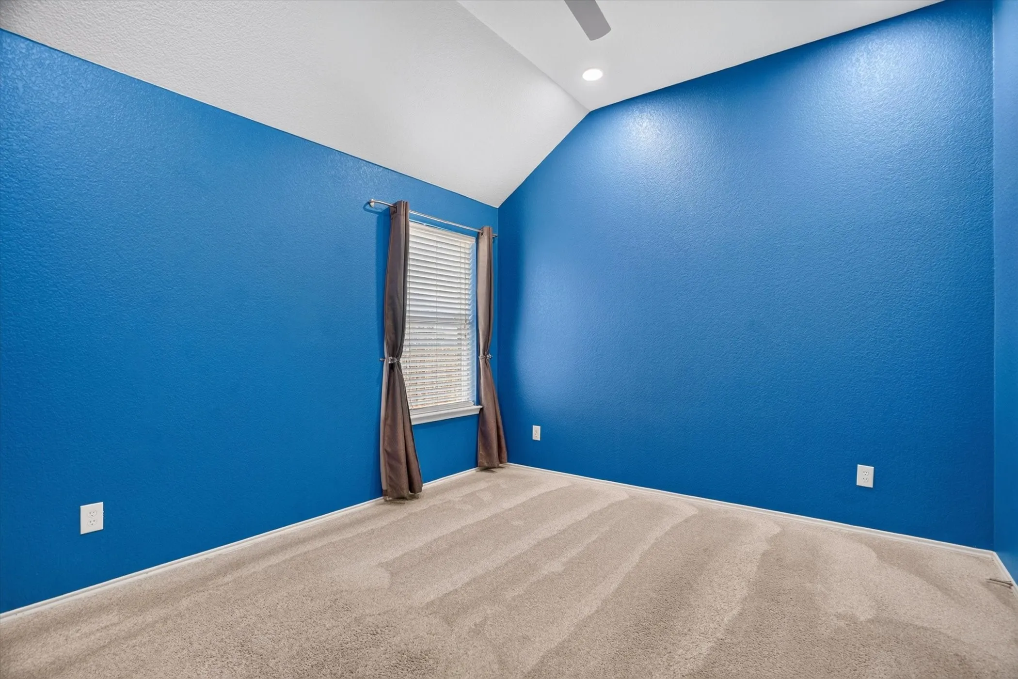 Vaulted ceiling with a ceiling fan, recessed lighting, and a single window with blinds