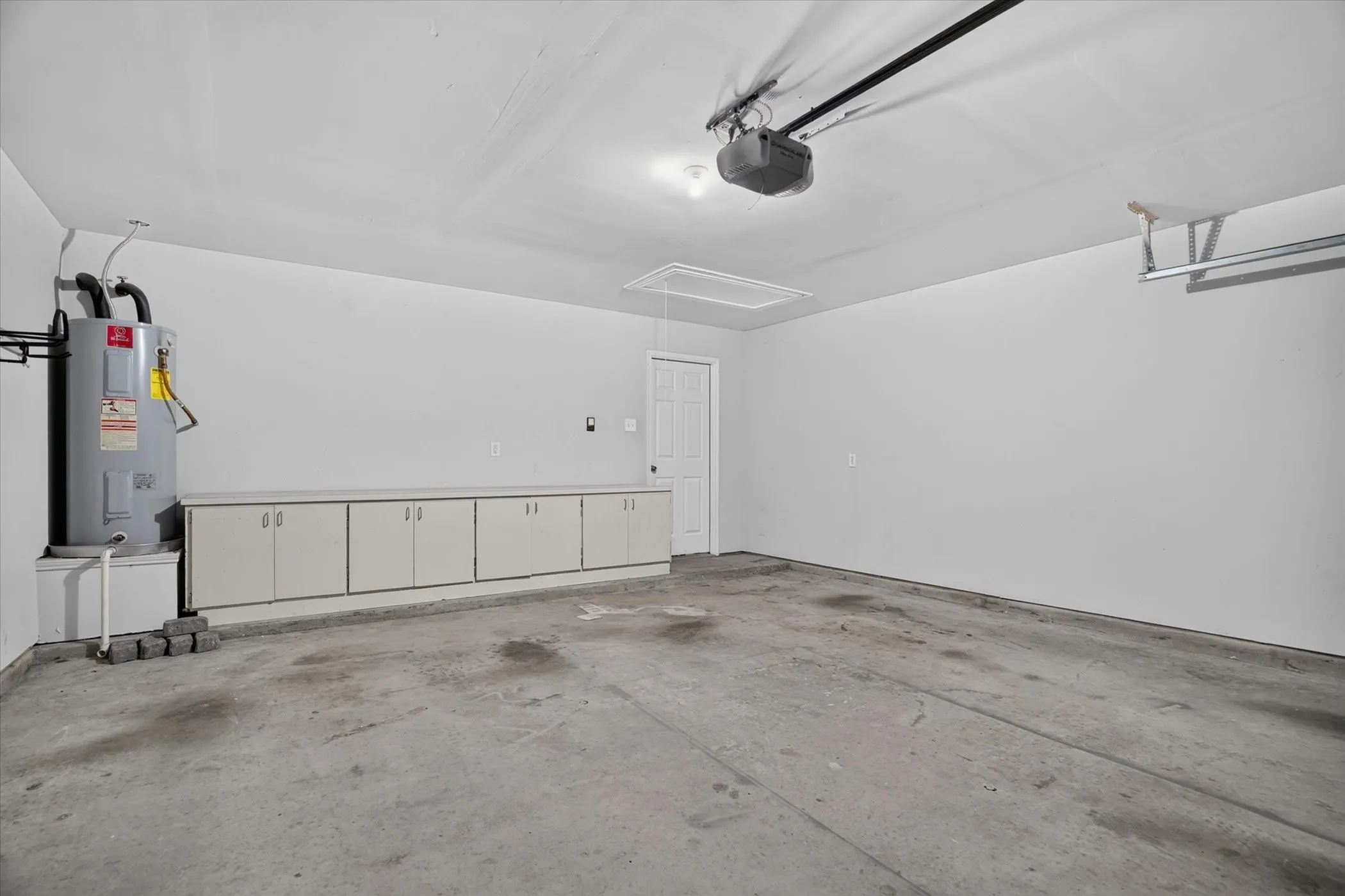 Integrated garage with a concrete floor, built-in cabinetry, overhead lighting, and an automatic garage door opener