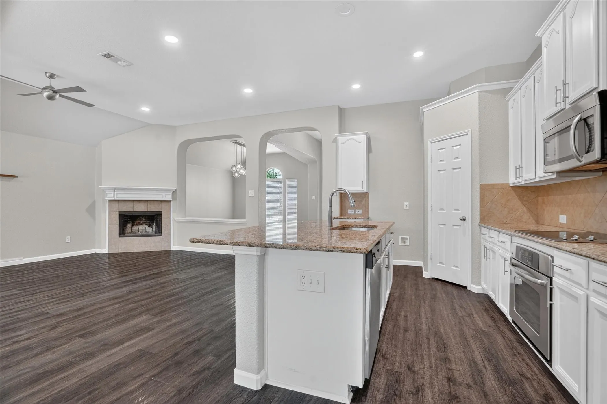 Kitchen island with granite countertops, stainless steel appliances, and white cabinetry