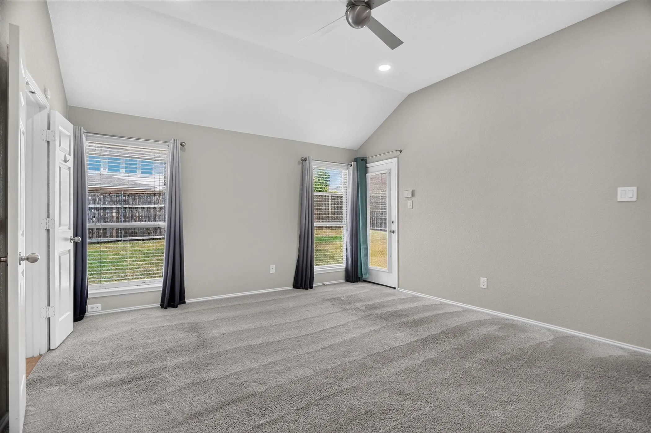 Virtually staged Vaulted ceiling with a ceiling fan, carpet flooring, dual windows with blinds, and double doors