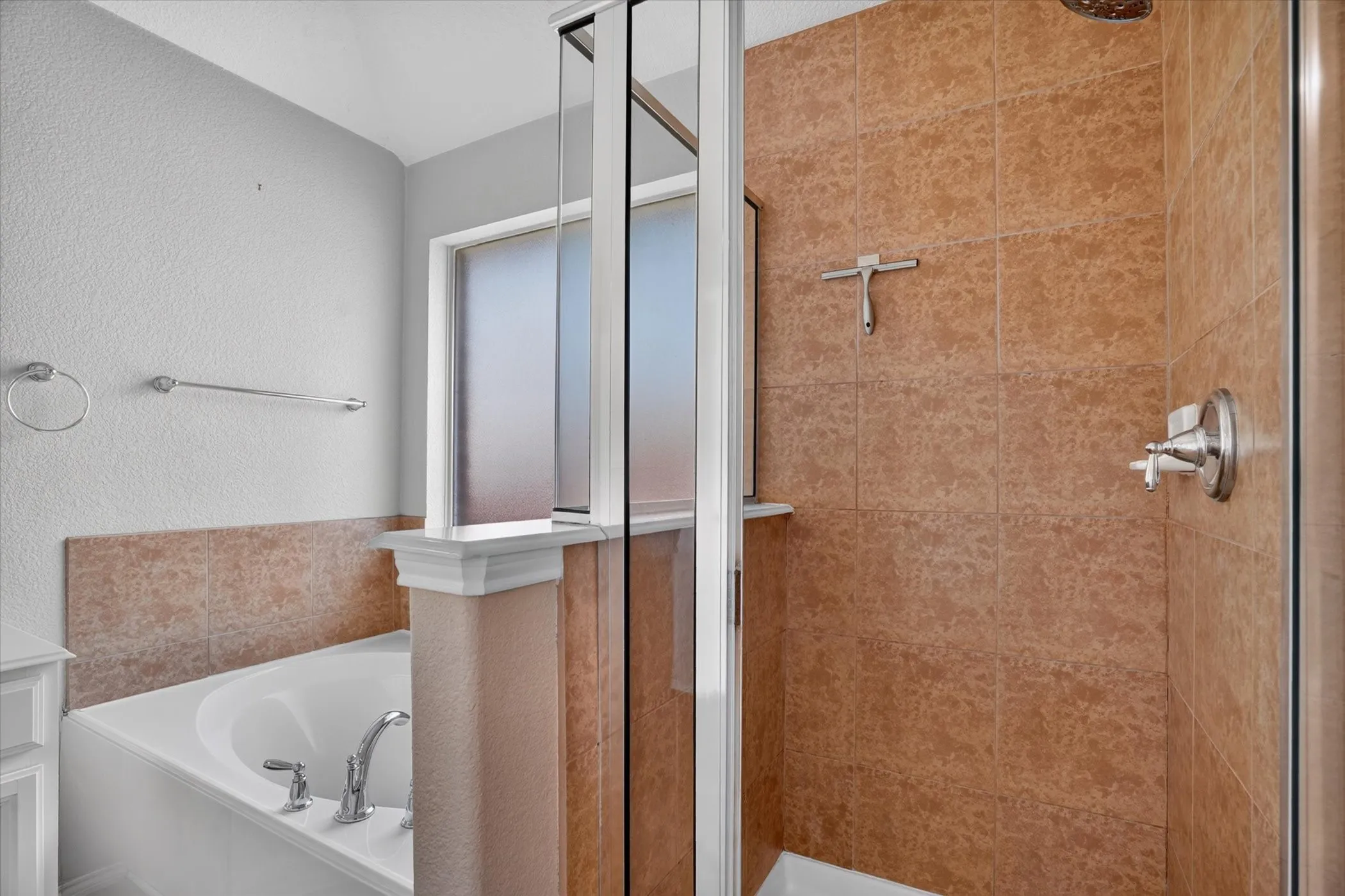 Soaking tub with chrome fixtures, tiled shower surround, clear glass shower enclosure, and frosted​​‌​​​​‌​​‌‌​‌‌​​​‌‌​‌​‌​‌​​​‌​​ window