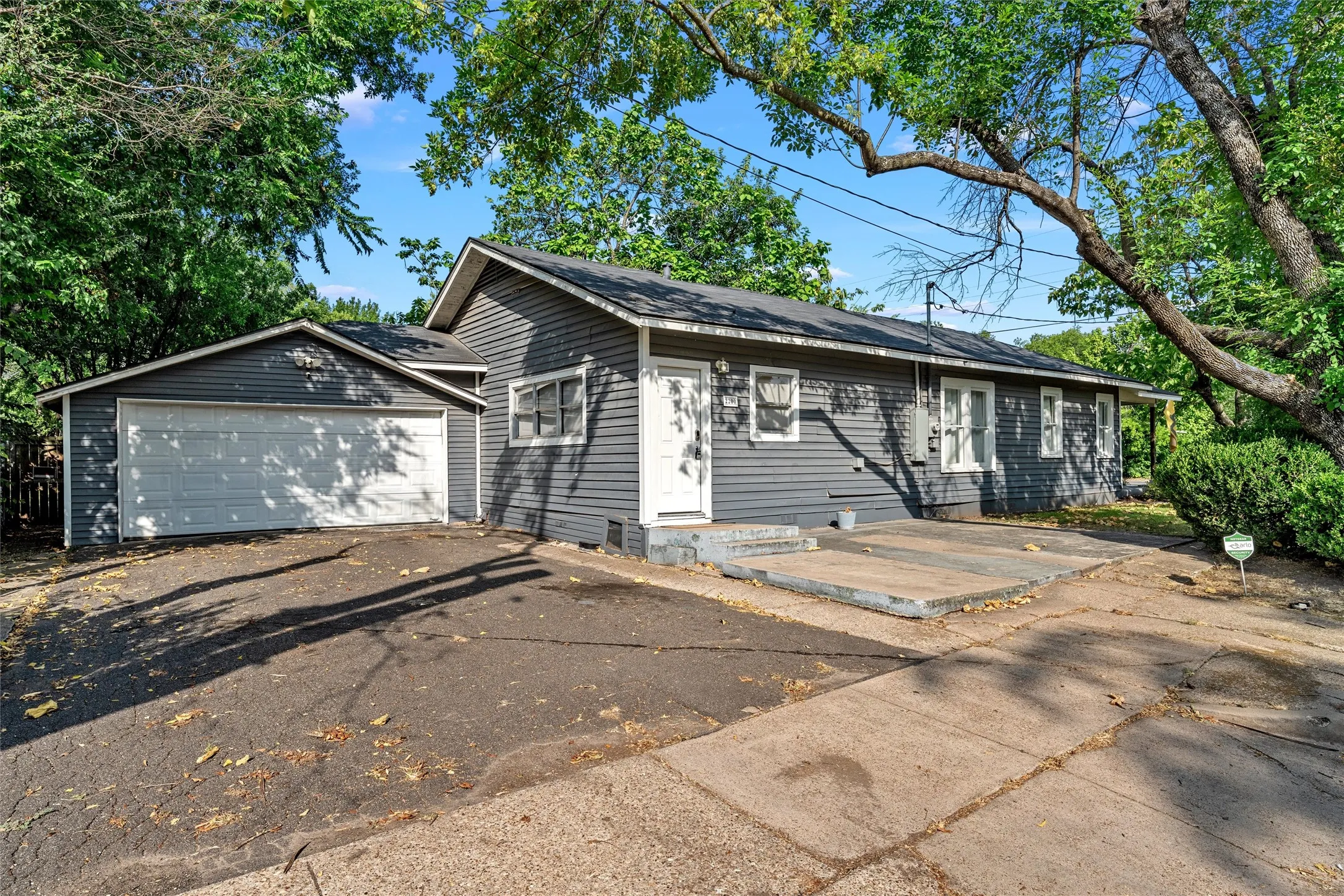 Single-story residence featuring horizontal siding, a gabled roofline, an attached garage with a white overhead door, and a paved driveway