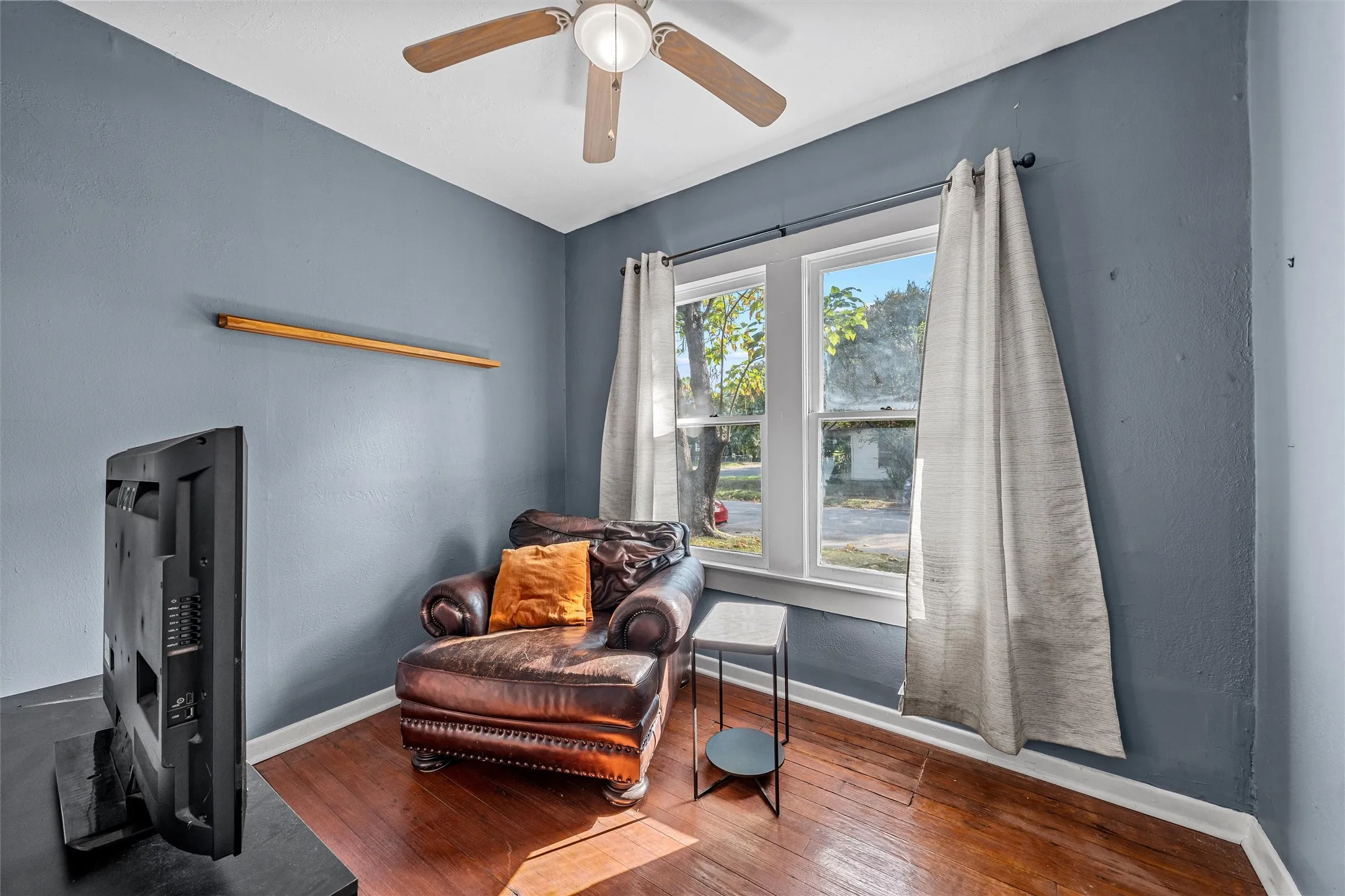 Hardwood-finish flooring, dual windows, and a ceiling fan with integrated lighting