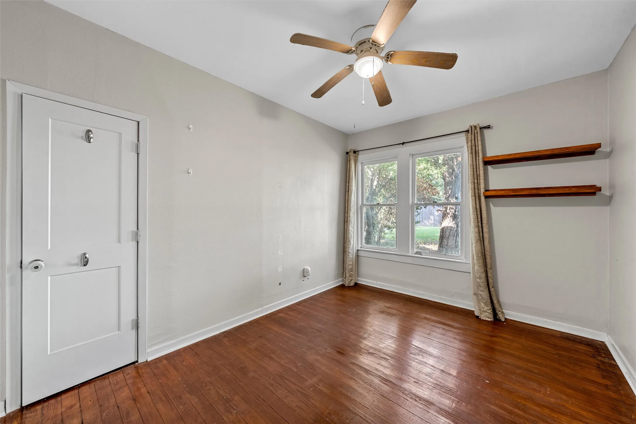 Hardwood flooring, ceiling fan with light fixture, double-hung windows, and built-in shelving