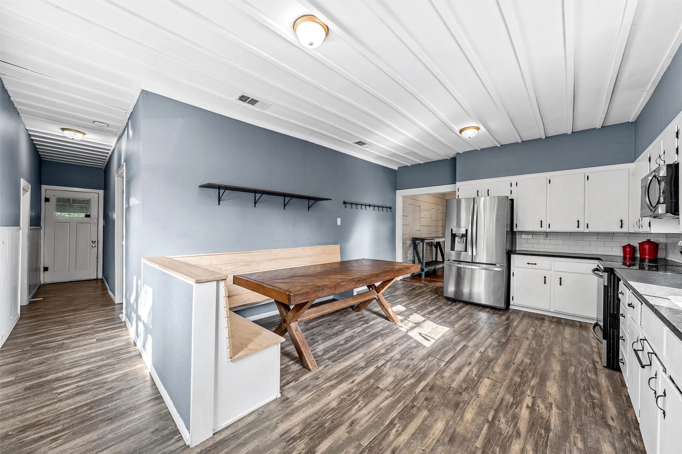 Kitchen featuring white cabinetry, dark countertops, a subway tile backsplash, and stainless steel appliances