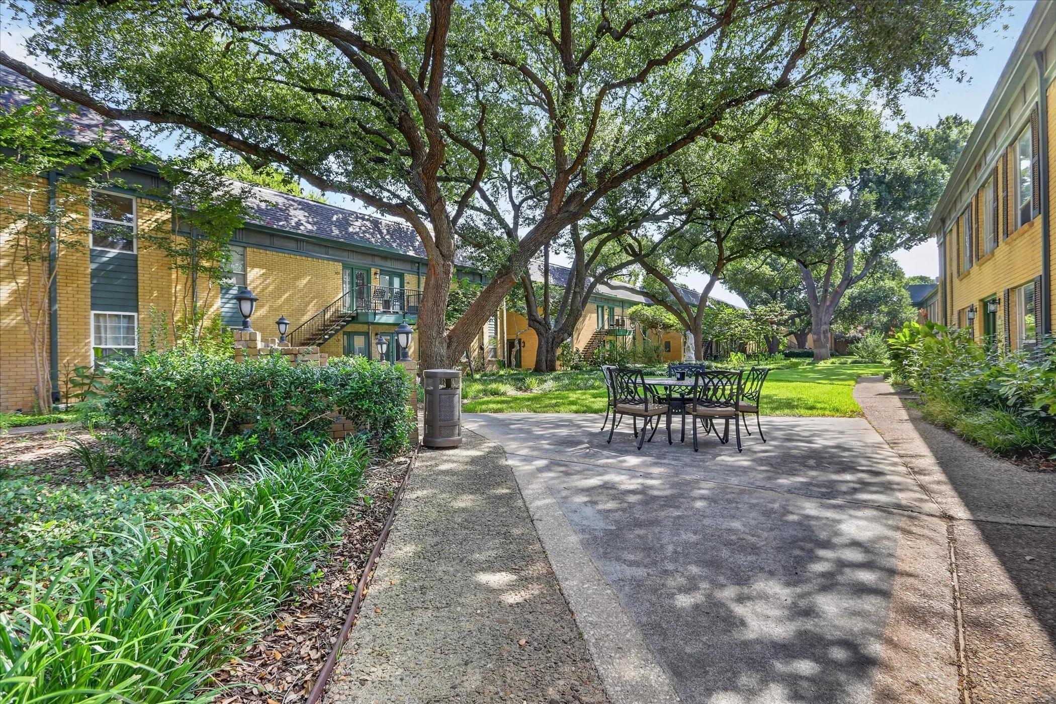 Tree-lined courtyard at 6020 E University Blvd Dallas TX 75206  Mature live oaks, landscaped walkways, and outdoor seating in gated East Dallas condo community.