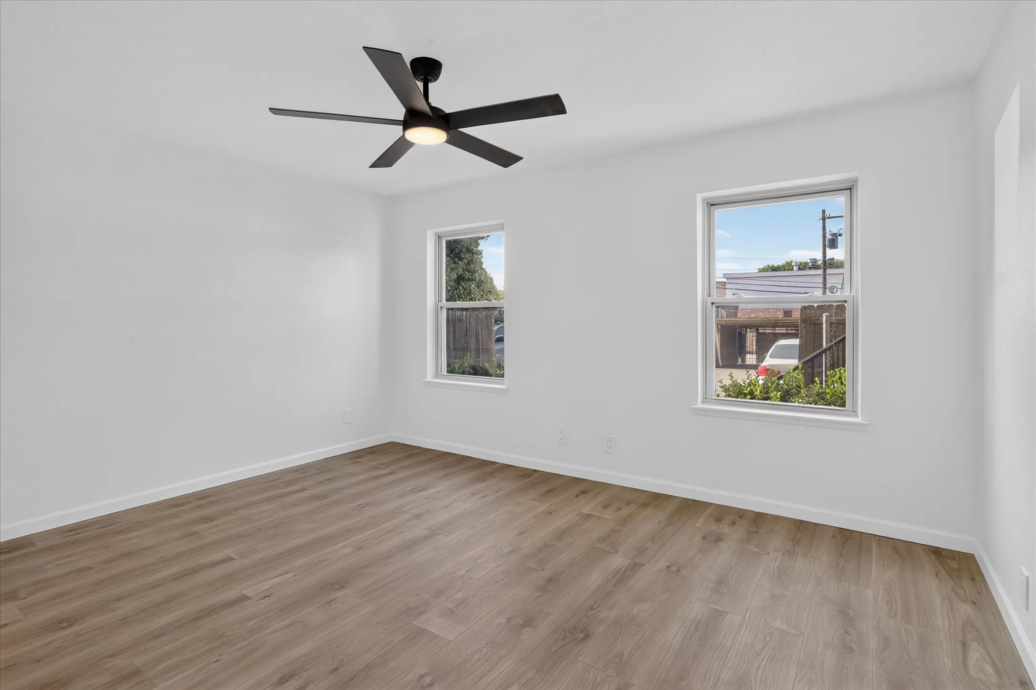 Secondary bedroom at 6020 E University Blvd Unit 117 Dallas TX 75206 — new LVP flooring, ceiling fan, two windows, and open closet — bright and move-in ready.