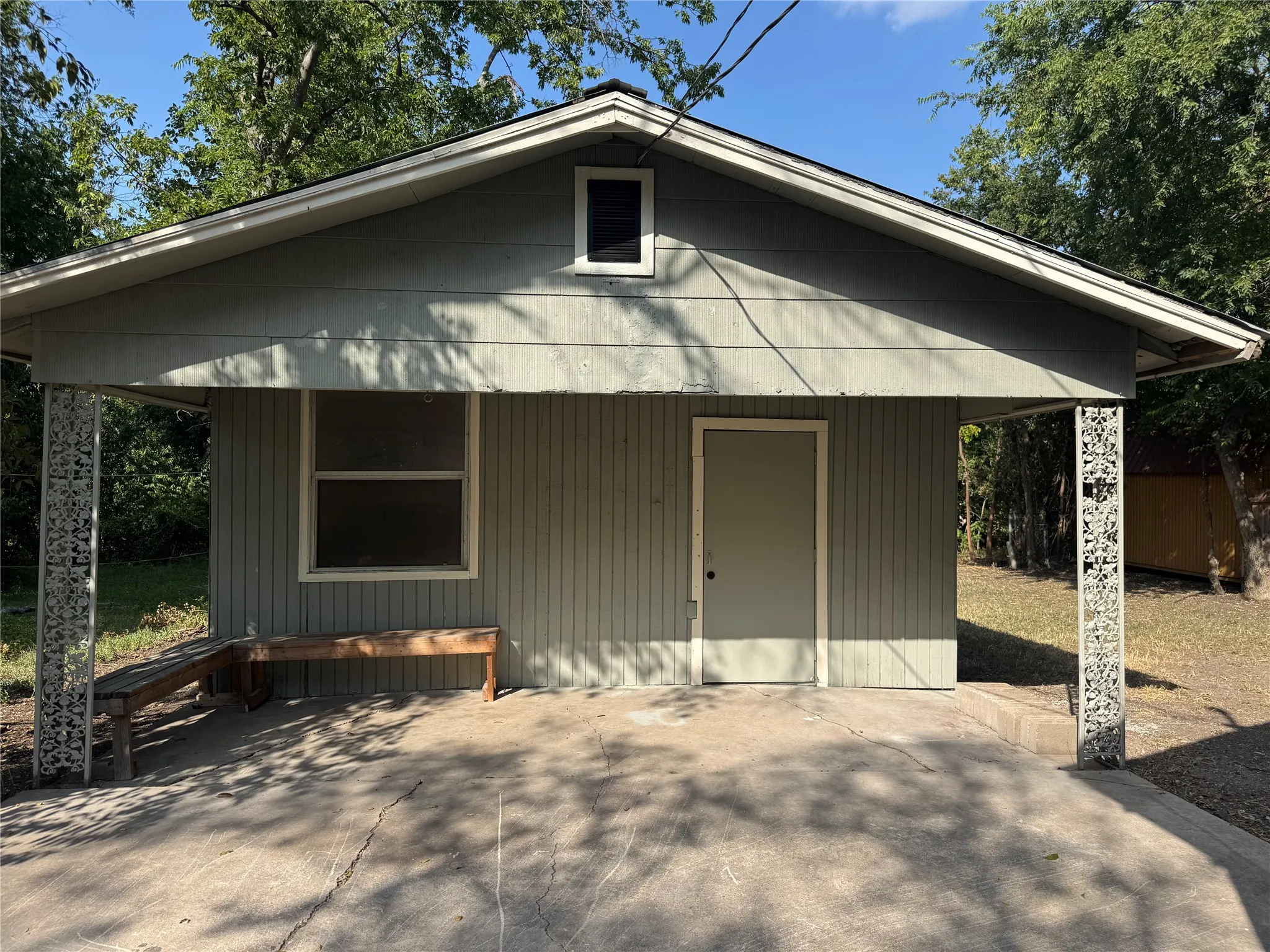 Carport featuring decorative metal support columns and a concrete floor