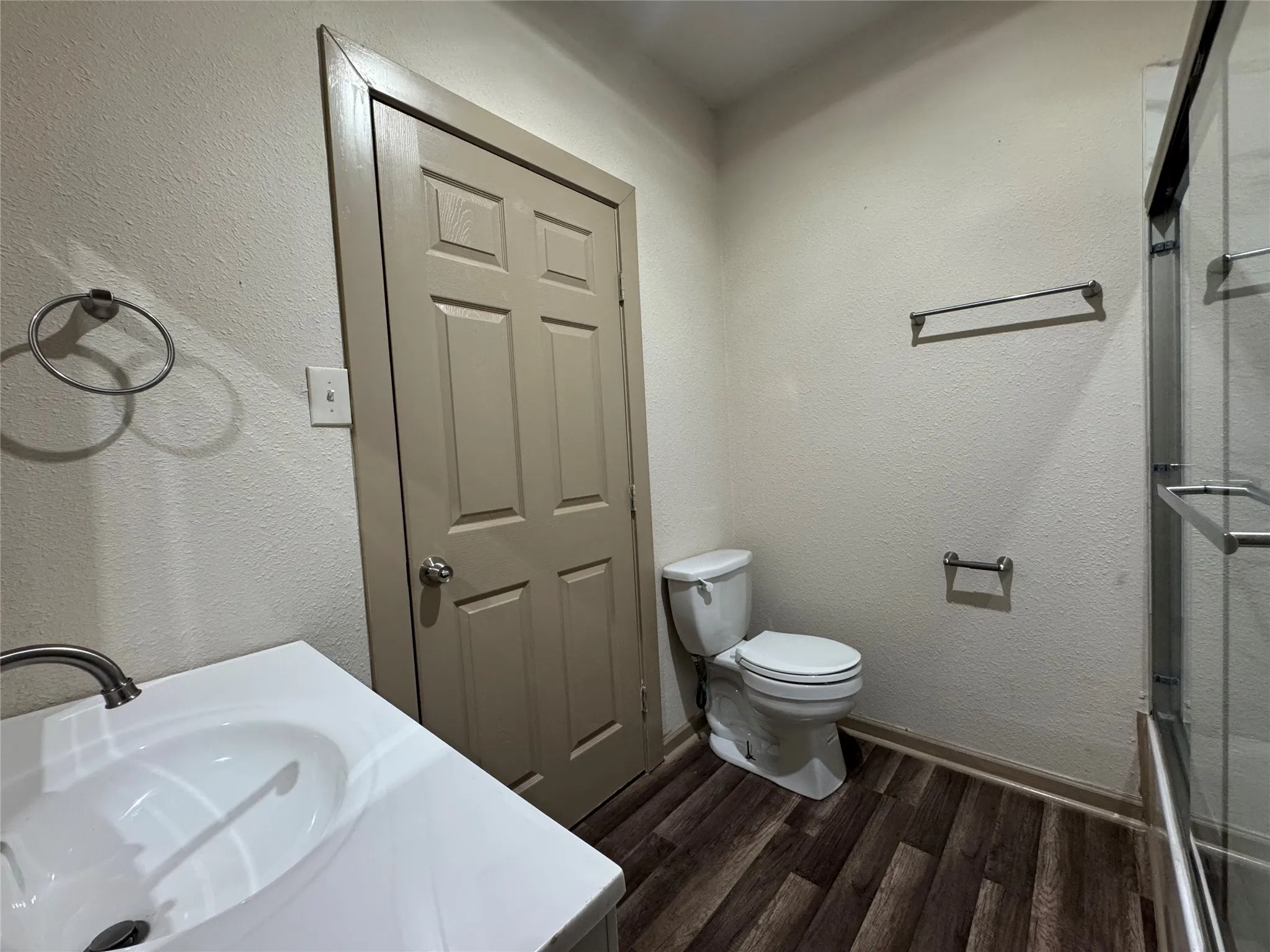 Vanity with integrated sink, wood-finish flooring, and glass-enclosed shower