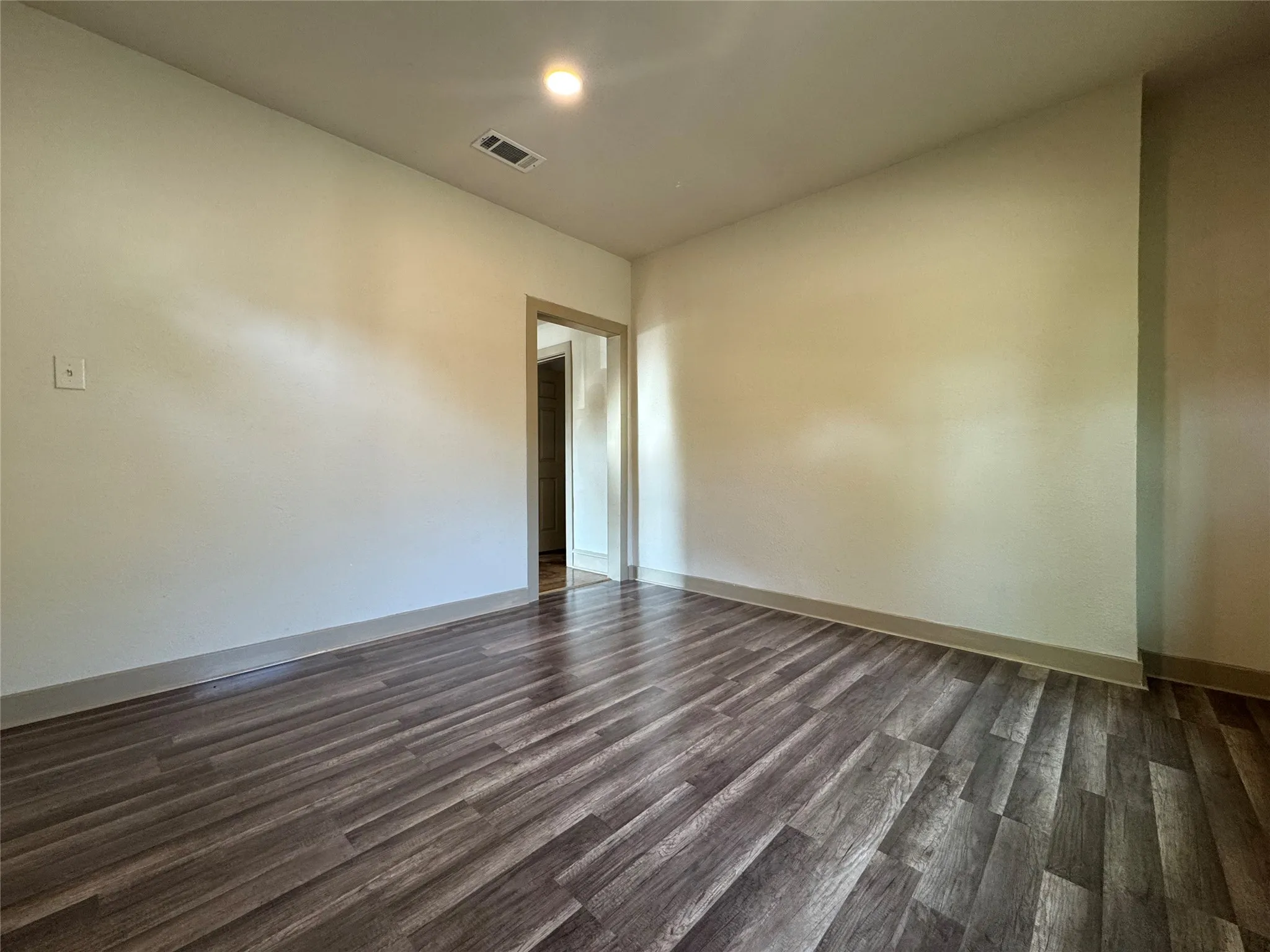 Spacious room featuring wood-finish flooring, light-toned walls, and recessed lighting