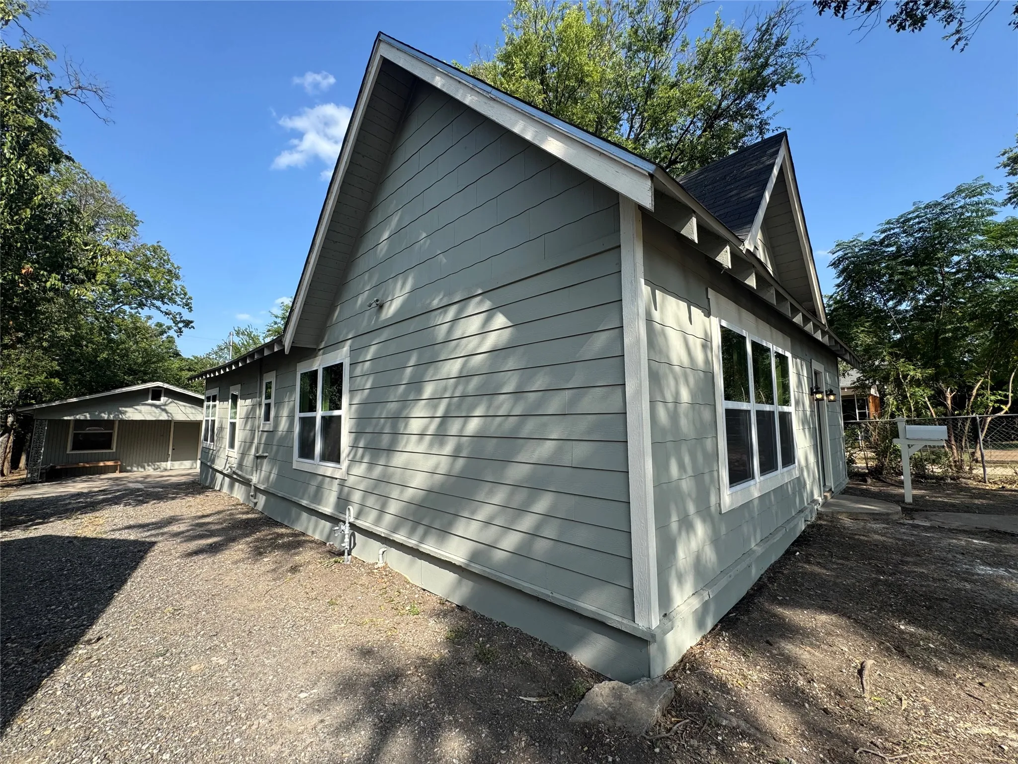 Light gray siding exterior with white window trim, multiple windows, and a dark shingle roof