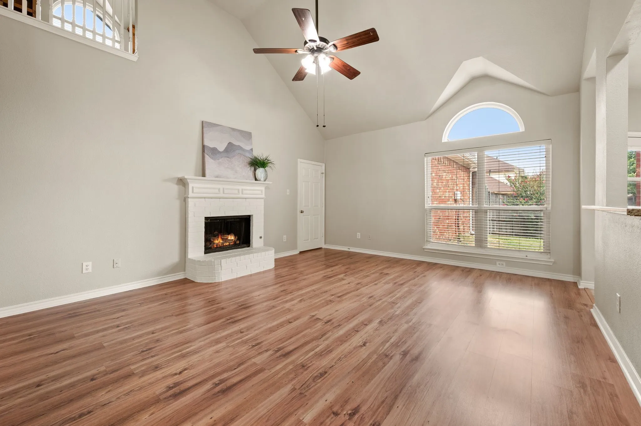 Spacious living area featuring high vaulted ceilings, wood-finish flooring, and a ceiling fan