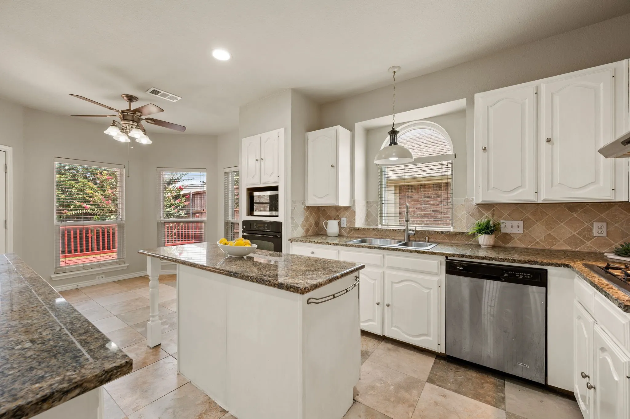 Kitchen featuring white cabinetry, granite countertops, a central island, stainless steel dishwasher, and tile flooring