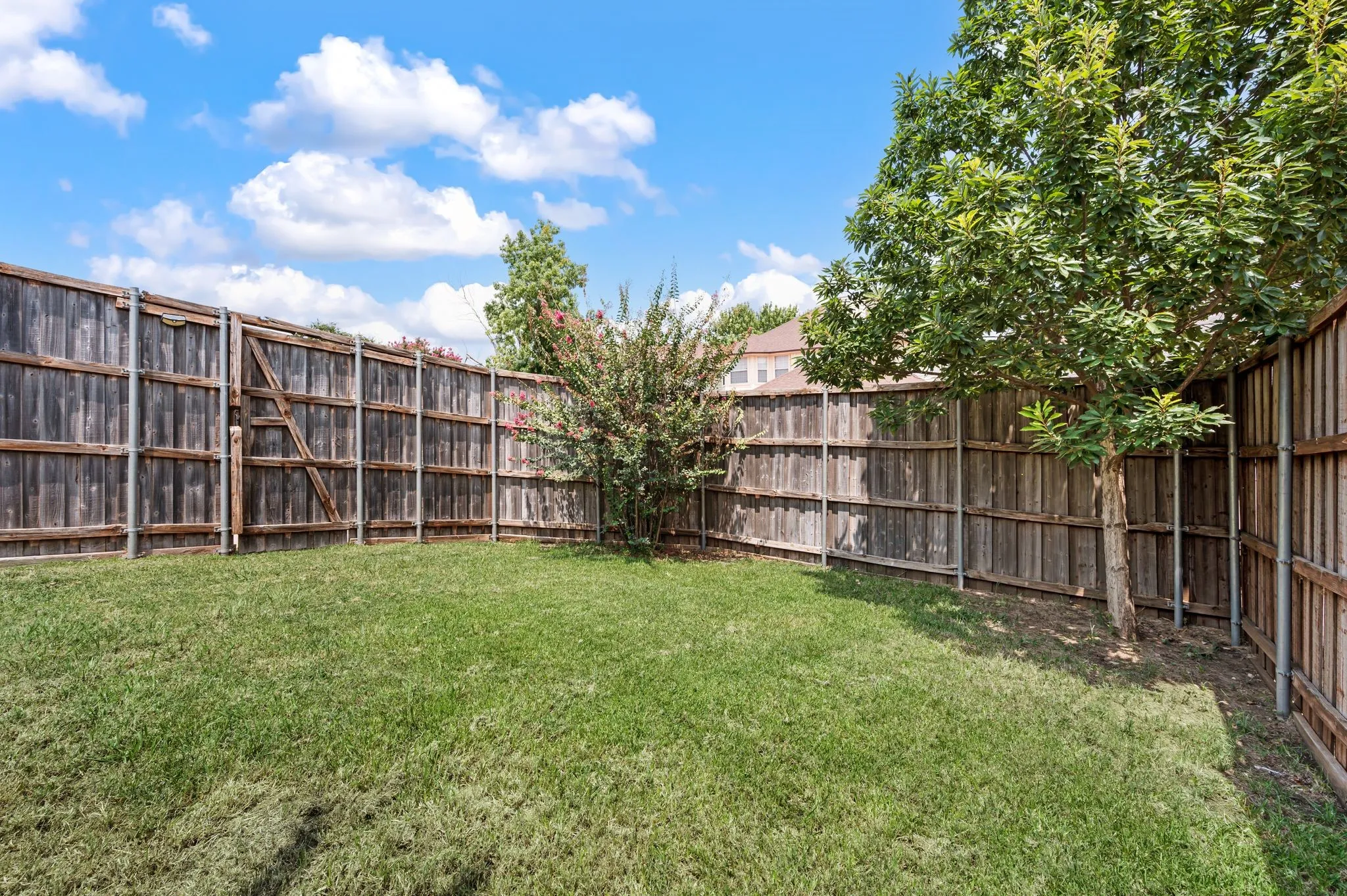 Expansive backyard featuring a mature, well-established lawn bordered by weathered wood privacy fencing on three sides