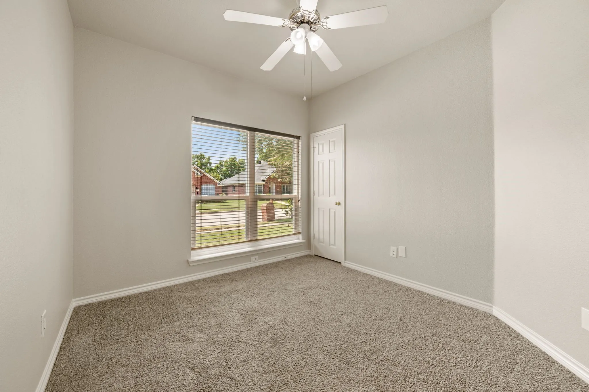 Bedroom featuring light neutral wall paint, gray carpeting, a multi-pane window with horizontal blinds, white trim, and a ceiling fan with light fixture