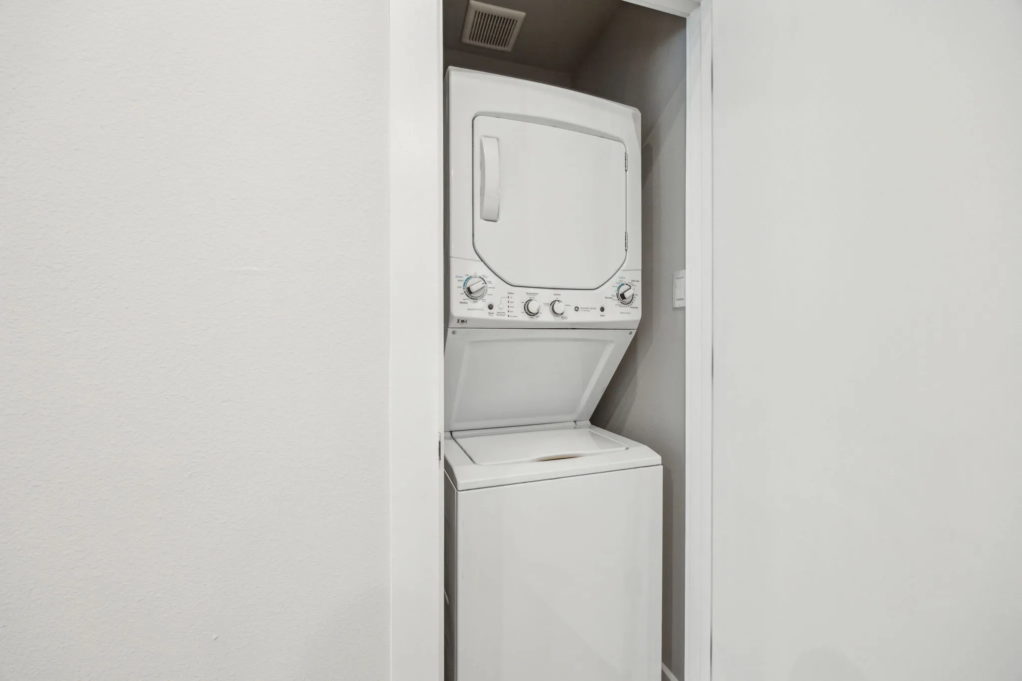 Stacked laundry appliances set within a dedicated alcove