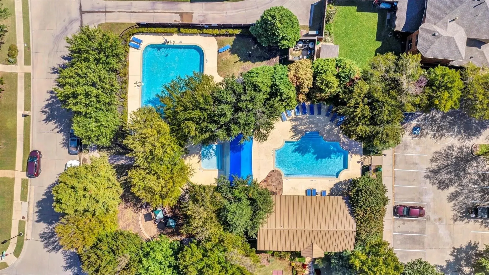 Community amenities include multiple swimming pools, extensive landscaping, a paved parking area, and mature trees