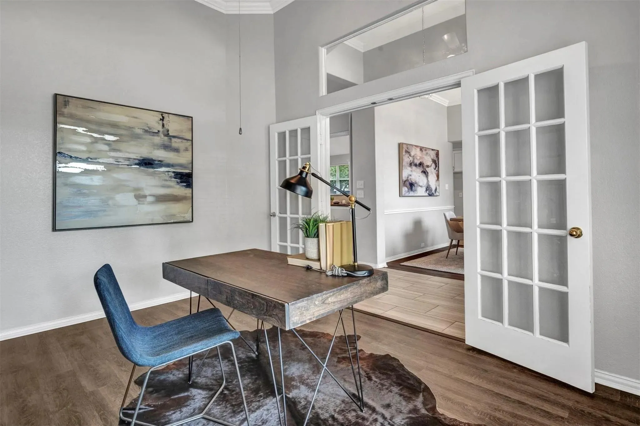 Wood-finish flooring with crisp white baseboards, vaulted ceilings, and double French doors with transom window