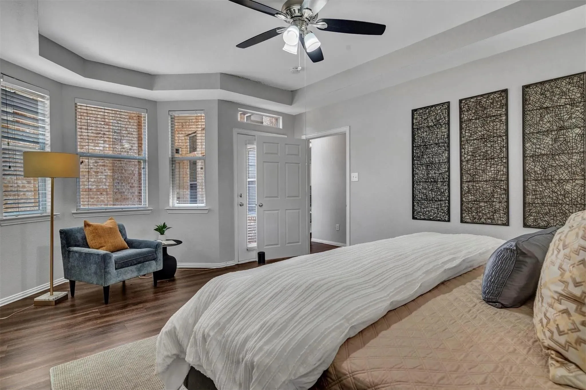 Tray ceiling, wood-finish flooring, ceiling fan with integrated lighting, double entry door, multiple windows with blinds