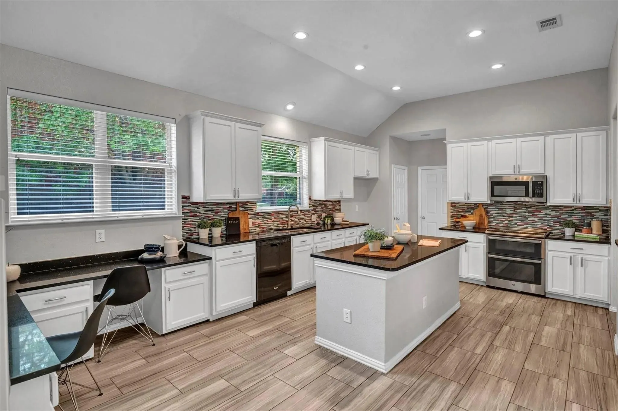 Kitchen featuring a central island, recessed lighting, wood-finish flooring, white cabinetry, and stainless steel appliances