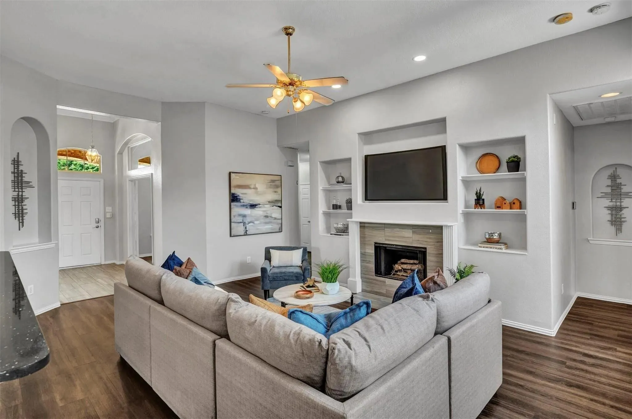 Open-concept living room anchored by a linear fireplace with built-in shelving and a mounted television